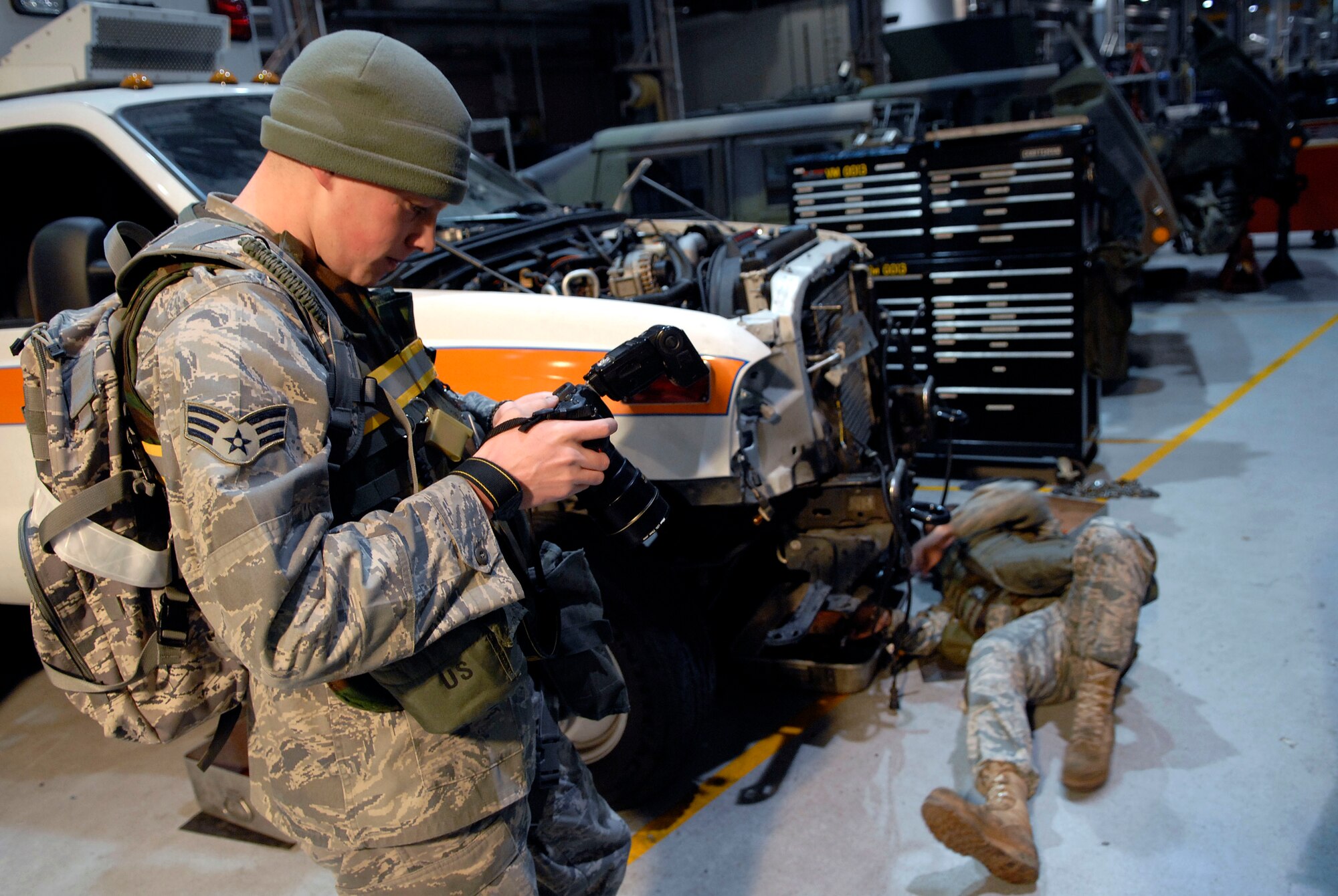 Senior Airman Christopher Boitz checks his photographs as a vehicle maintainer disassembles the cooling system of an ambulance during the 51st Fighter Wing’s Operational Readiness Exercise Beverly Midnight 09-01 at Osan AB, Republic of Korea, Feb. 8. Airman Boitz is assigned to the 51st Fighter Wing, Public Affairs office.  (U.S. Air Force photo/Staff Sgt. Brian Ferguson)
 
