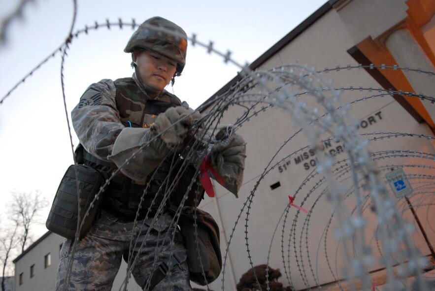 Master Sgt. Cresencio Kirby lays concertina wire outside the 51st Mission Support Squadron's entry control point in preparation for the 51st Fighter Wing’s Operational Readiness Exercise Beverly Midnight 09-01 at Osan AB, Republic of Korea, Feb. 8.  Concertina wire is a defensive obstacle designed to disrupt, delay and generally slow down enemy. Sergeant Kirby is assigned to the 51 MSS.   (U.S. Air Force photo/Staff Sgt. Brian Ferguson)
 

