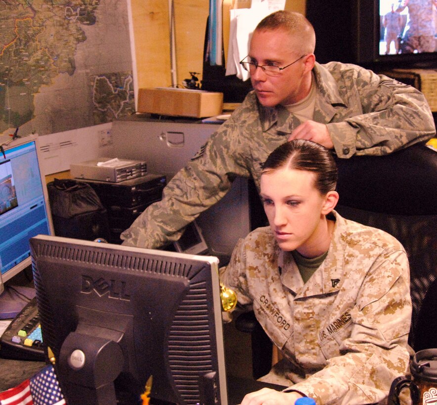 Cpl. Kimberly Crawford, a combat correspondent stationed at Camp Lejuene, N.C., edits video with assistance from Air Force Staff Sgt. Jeff St. Sauveur at Bagram Airfield, Afghanistan Feb. 14.::n::
