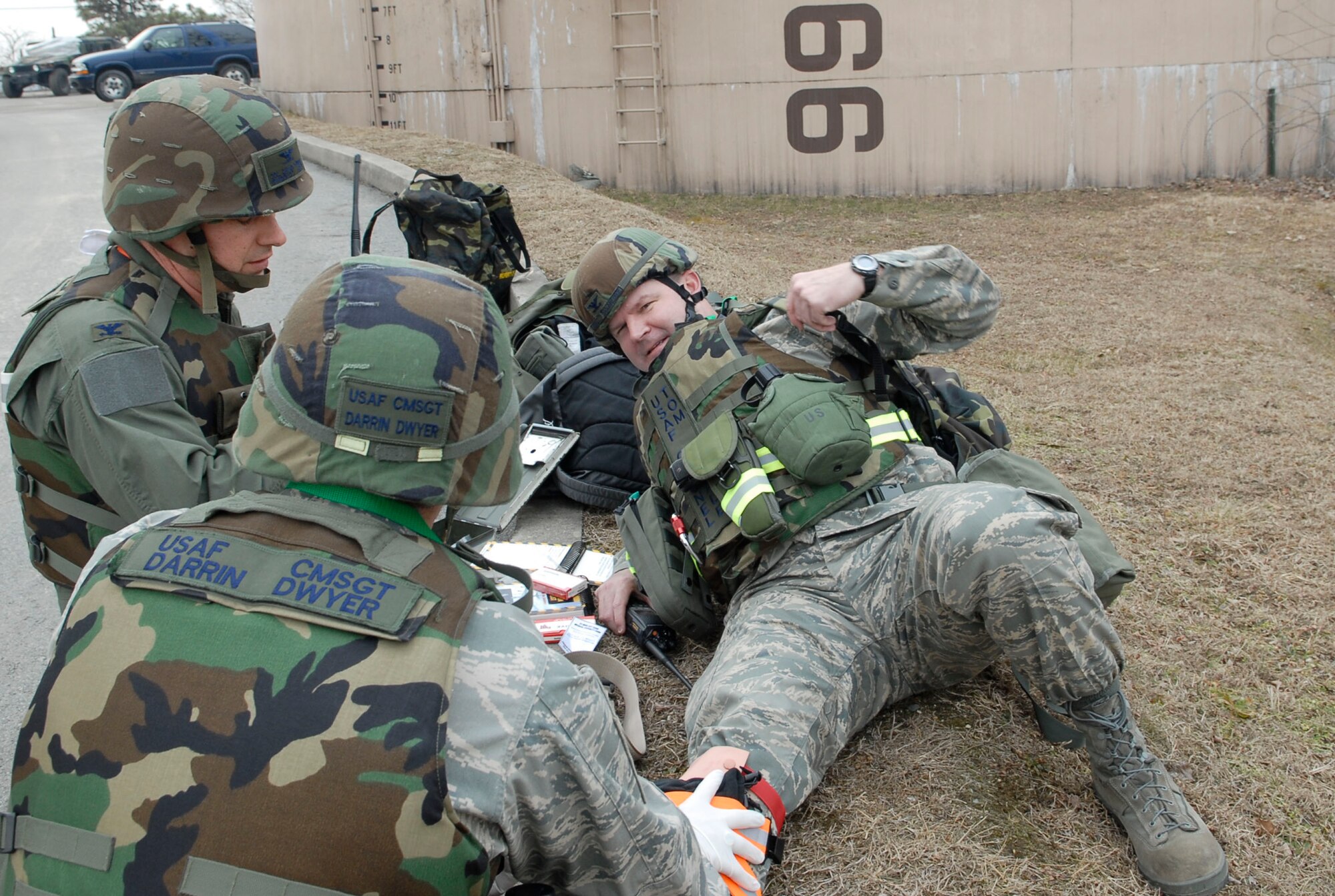 Chief Master Sgt. Darrin Dwyer, (left), and Col. David O?Brien perform  self aid and buddy care on Col. Thomas Deale for a simulated broken leg during a ?Bug out? of the Emergency Operations Center during the 51 FW Operational Readiness Exercise Beverly Midnight 09-01 at Osan, Air Base, Republic of Korea Feb 09. "Bug-out" drills are conducted to demonstrate the effectiveness of building occupants to evacuate quickly from a building as quickly and safely as possible. Colonel Deale is the 51st FW Commander, Colonel O?Brien is the 51st Medical Group commander and Chief Master Sergeant Dwyer is the 51st Fighter Wing Command Chief Master sergeant. (US Air Force photo by Staff Sgt. Scottie T. McCord)