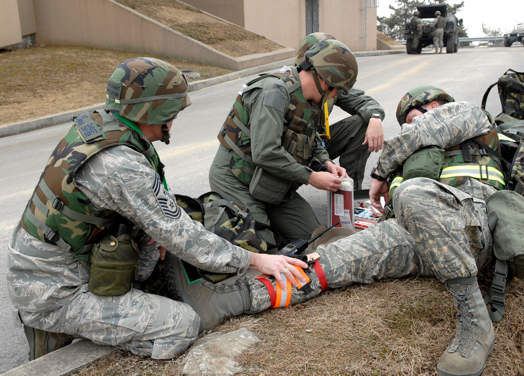 Chief Master Sgt. Darrin Dwyer, (left), and Col. David O?Brien, (center), self aid and buddy care on Col. Thomas Deale for a simulated broken leg during a ?Bug out? of the Emergency Operations Center during the 51 FW Operational Readiness Exercise Beverly Midnight 09-01 at Osan, Air Base, Republic of Korea Feb 09. "Bug-out" drills are conducted to demonstrate the effectiveness of building occupants to evacuate quickly from a building as quickly and safely as possible. Colonel Deale is the 51st FW Commander, Colonel O?Brien is the 51st Medical Group commander and Chief Master Sergeant Dwyer is the 51st Fighter Wing Command Chief Master sergeant. (US Air Force photo by Staff Sgt. Brian Ferguson)