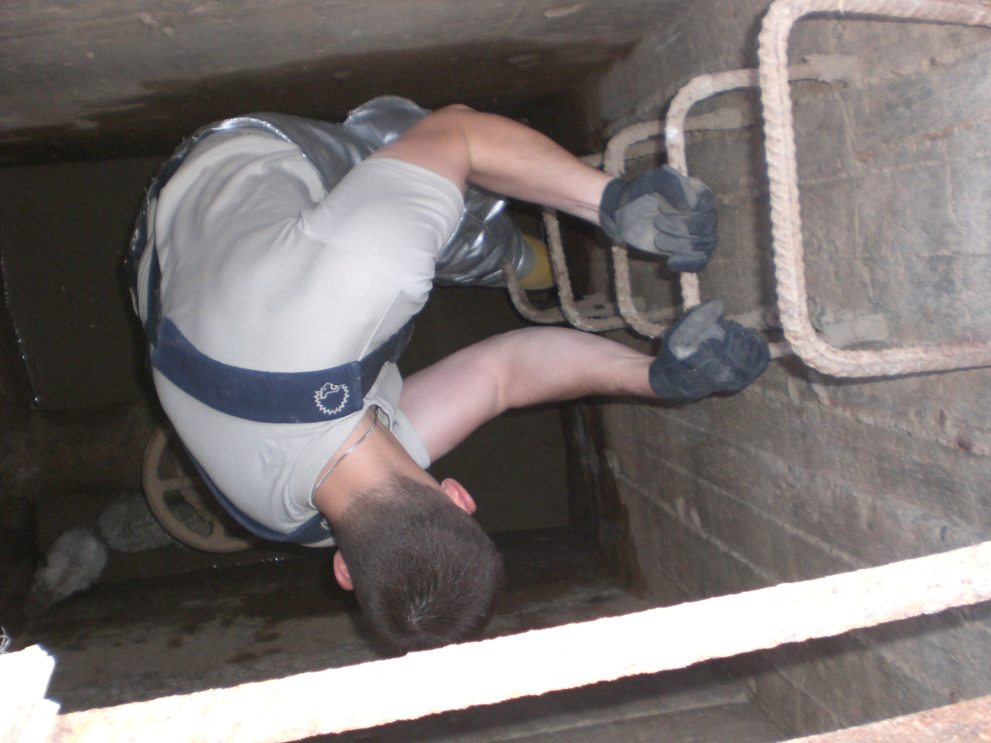 Staff Sgt. Bryan Senecal, 407th Expeditionary Civil Engineer Squadron Fire and Rescue Services crew chief, decends into a manhole to rescue a baby camel trapped at the bottom. (U.S. Air Force photo)