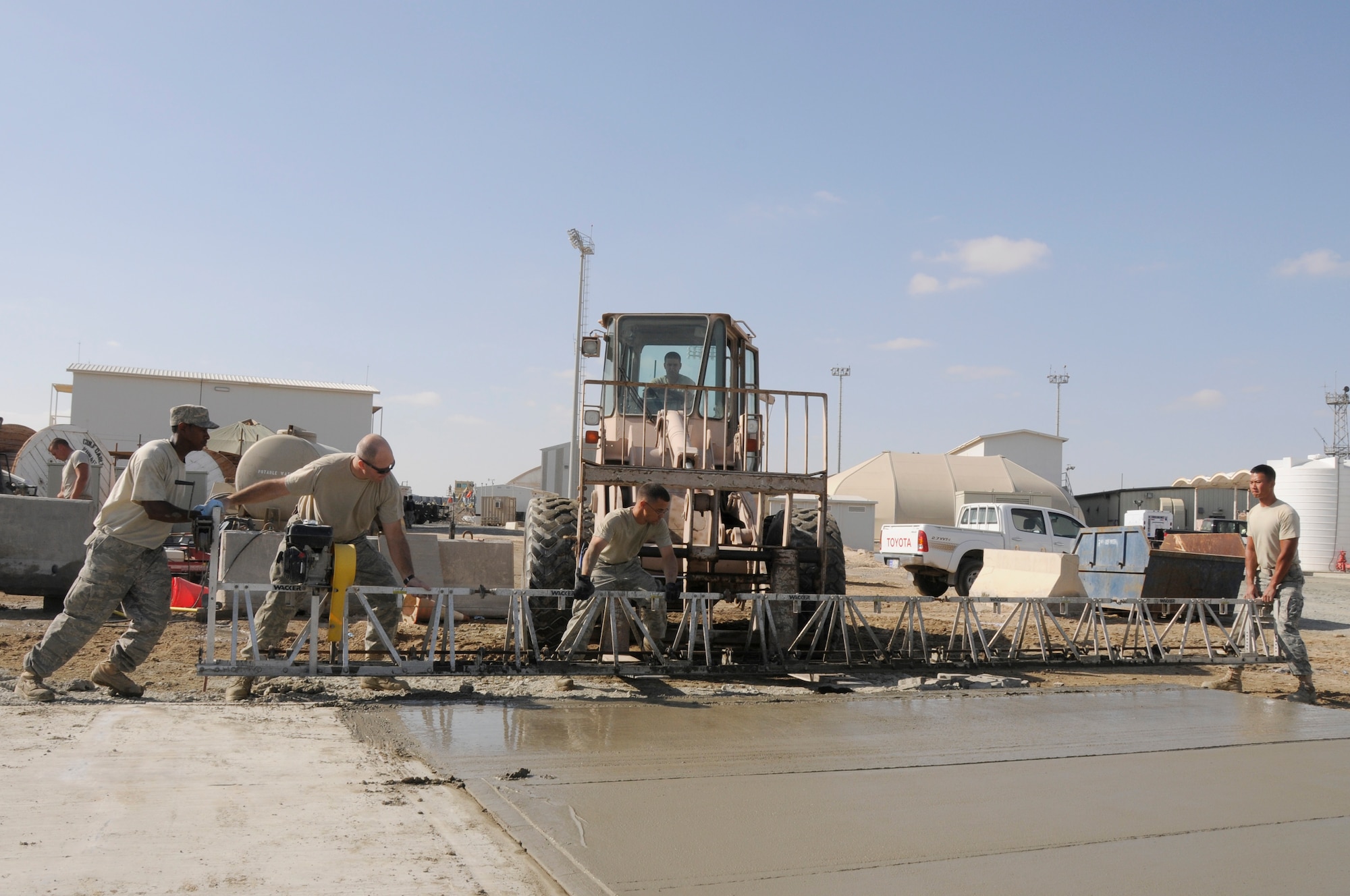 SOUTHWEST ASIA - Members of the 380th Expeditionary Civil Engineer Squadron, pavement and heavy equipment lift a screed after leveling a slab of concrete, Feb 5. The screed consolidates and levels the concrete to a flat surface. When finished the concrete slab will be used for a food storage area for the new dining facility at the 380th Air Expeditionary Wing. Sergeant Pallas is deployed from Ellsworth AFB and hails from Washington. Sergeant Pitt is deployed from Bolling AFB, DC and hails from Virginia Beach, Va. Airman Batista is deployed from Andrews AFB, Md. and hails from Providence, R.I. (U.S. Air Force photo by Senior Airman Brian J. Ellis) (Released)