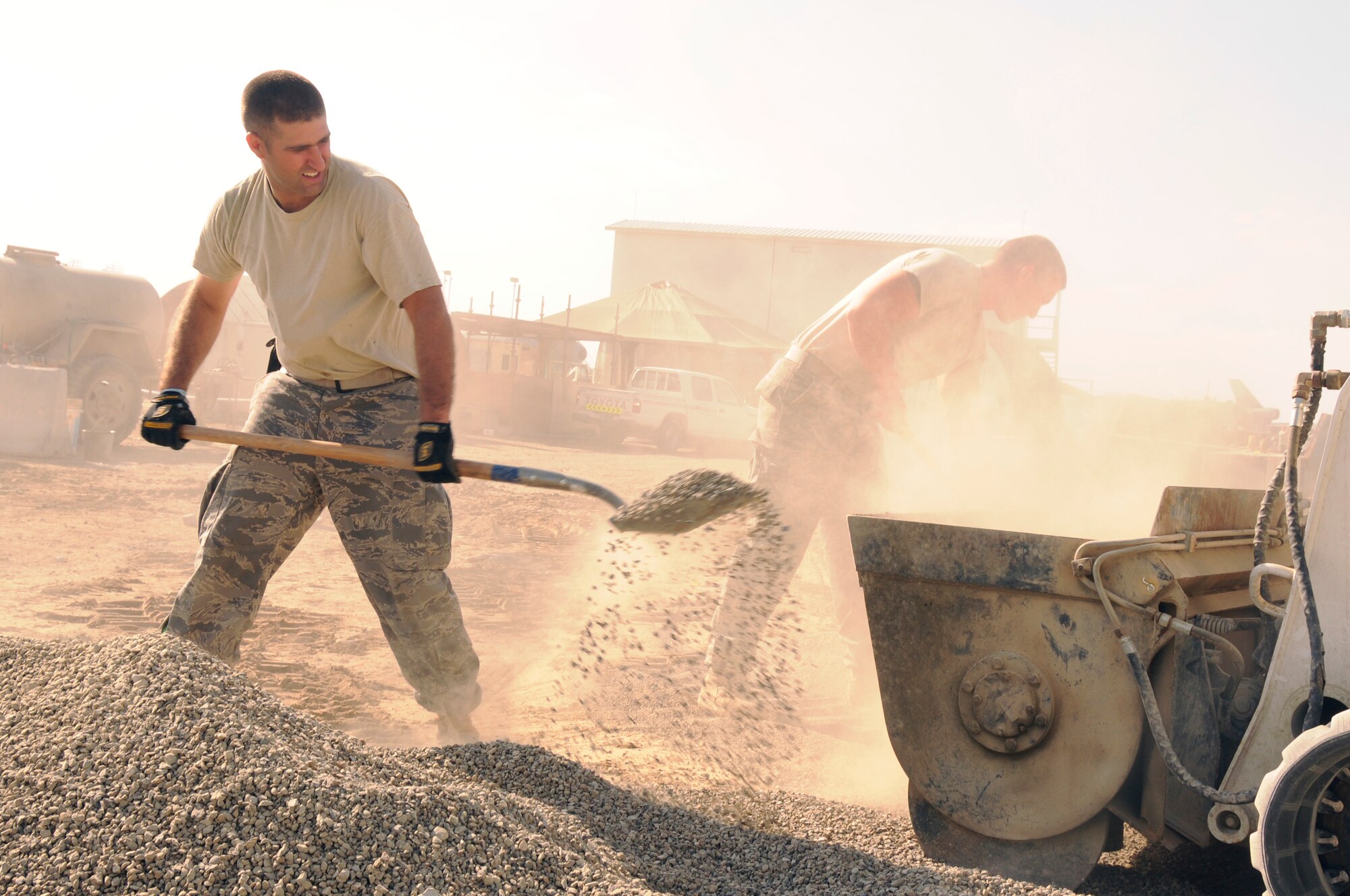 SOUTHWEST ASIA - Tech Sgt. Arthur Cronk and Airman 1st Class David Roberts, 380th Expeditionary Civil Engineer Squadron, pavement and heavy equipment operator's shovel gravel for a concrete mix into a Bobcat loader, Feb 5. The concrete mixture is 1 part cement, 2 parts sand and 3 parts gravel. When finished the concrete slab will be used for a food storage area for the new dining facility at the 380th Air Expeditionary Wing. Sergeant Cronk is deployed from Andrews AFB, Md. and hails from Great Falls, Mo. Airman Roberts is deployed from Bolling AFB, DC and hails from Bristol, Tenn.(U.S. Air Force photo by Senior Airman Brian J. Ellis) (Released)