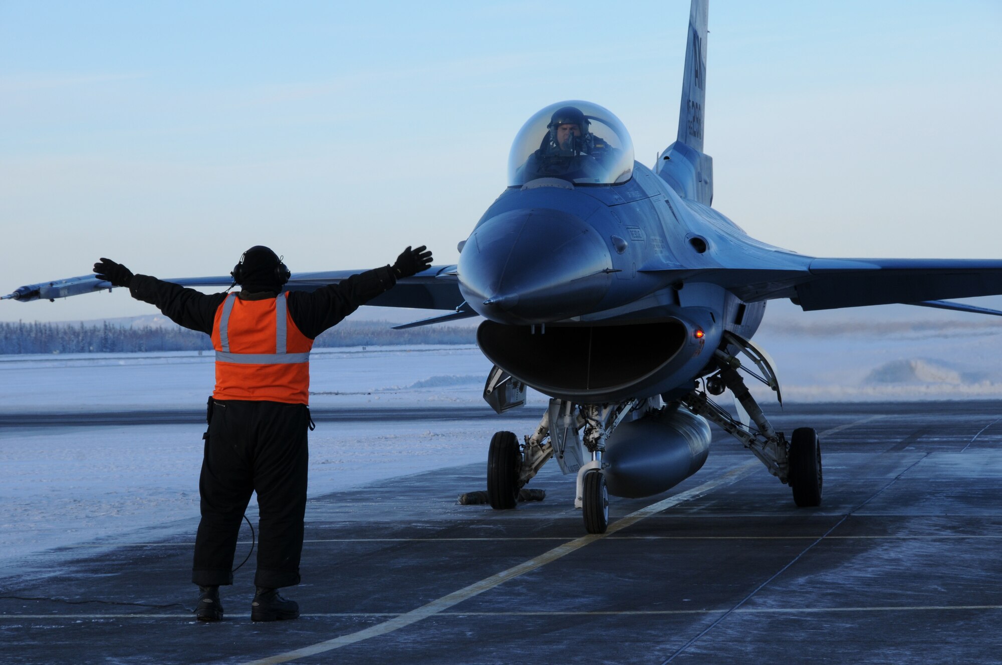 Staff Sgt. David Kessler marshals an F-16 Fighting Falcon Feb. 5, 2009 at Eielson Air Force Base, Alaska. Sergeant Kessler controls movement of the aircraft with hand signals for final safety checks at the end of the runway, as well as ensures crew safety. Sergeant Kessler is with the 354th Aircraft Maintenance Squadron. (U.S. Air Force photo/Airman 1st Class Laura Max)