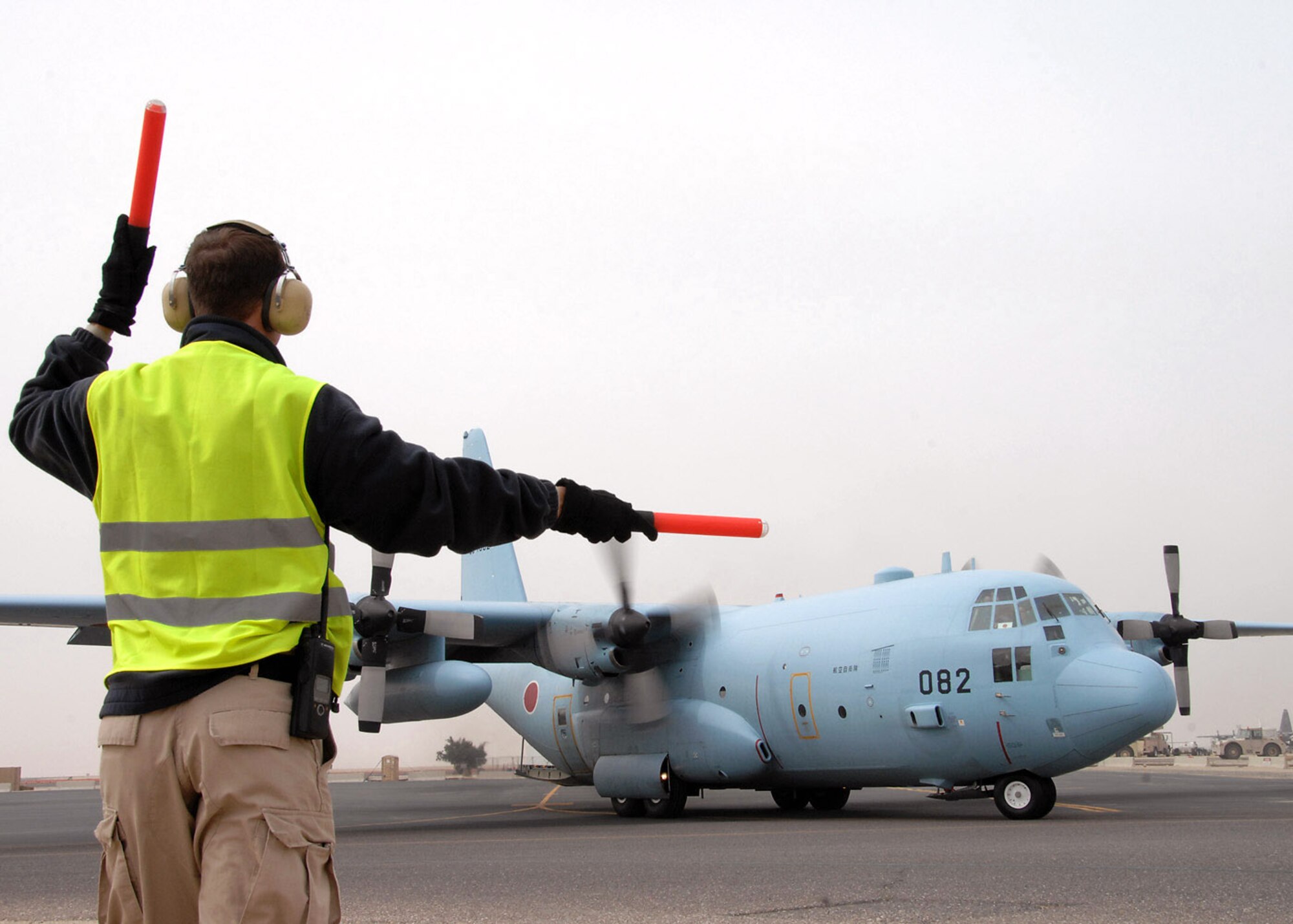 Jeff Schiebout guides a Japanese Air Self Defense Force C-130 as they taxi to the runway for their flight home at an air base in Southwest Asia, Feb. 10. Since 2004 the JASDF have been providing airlift for the coalition forces and United Nations in support of Iraqi reconstruction efforts. Mr. Schiebout is assigned to the 386th Expeditionary Maintenance Squadron Transient Alert. (U.S. Air Force photo/Senior Airman Courtney Richardson)