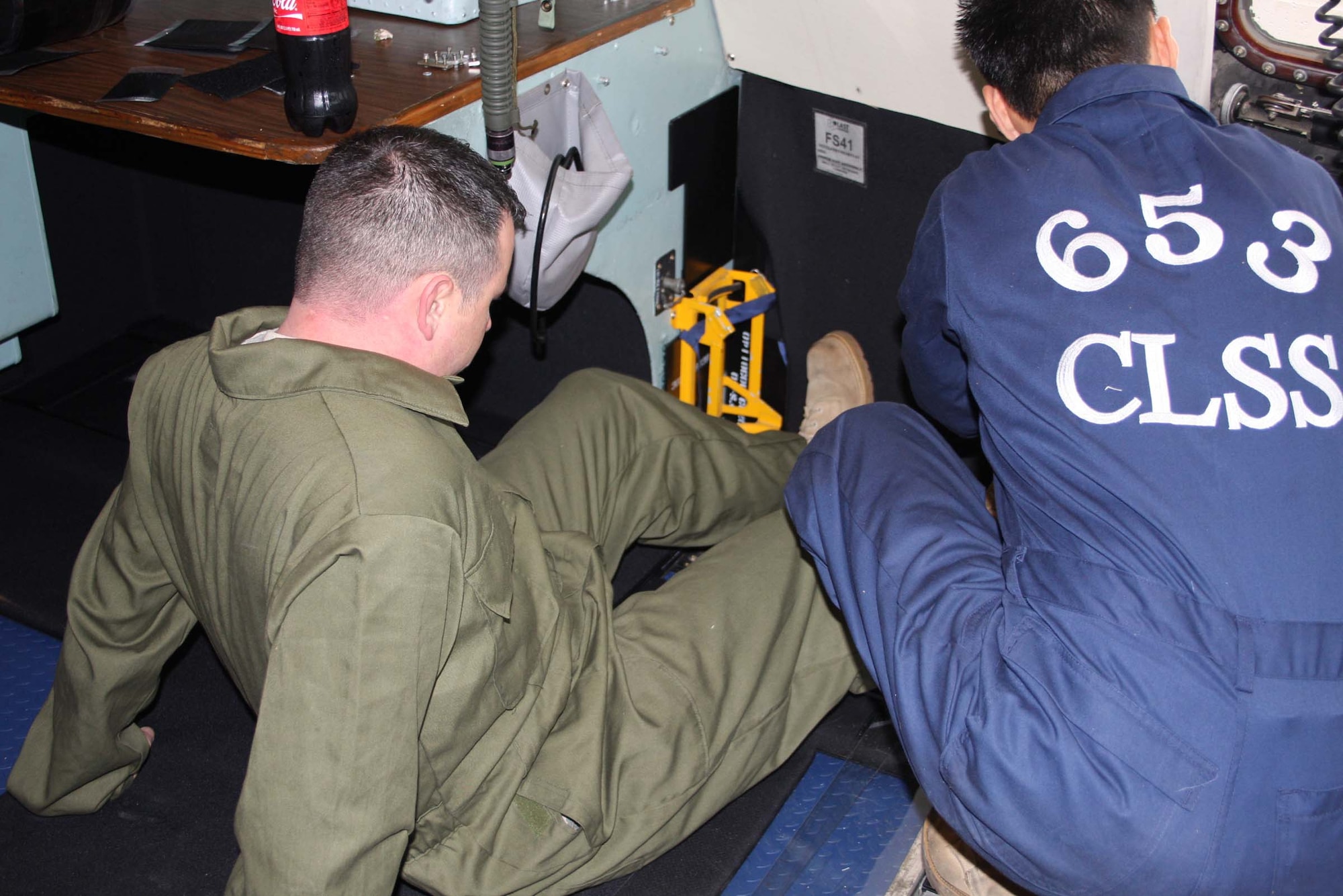 WRIGHT-PATTERSON AFB, Ohio – Tech. Sgt. Mark McQueen, left, and Tech. Sgt. Don Kim, both from the 653rd Combat Logistics Support Squadron, Robins Air Force Base, Ga., install armor on the flight deck of a C-5 Galaxy belonging to the 445th Airlift Wing.  Several pieces are put together like a big jigsaw puzzle to form the armor and connected with Velcro.  The armor will protect the flight crew from small arms fire from the ground and will reduce the threat of damage to vital, internal parts of the aircraft. (Air Force photo/Stacy Vaughn)