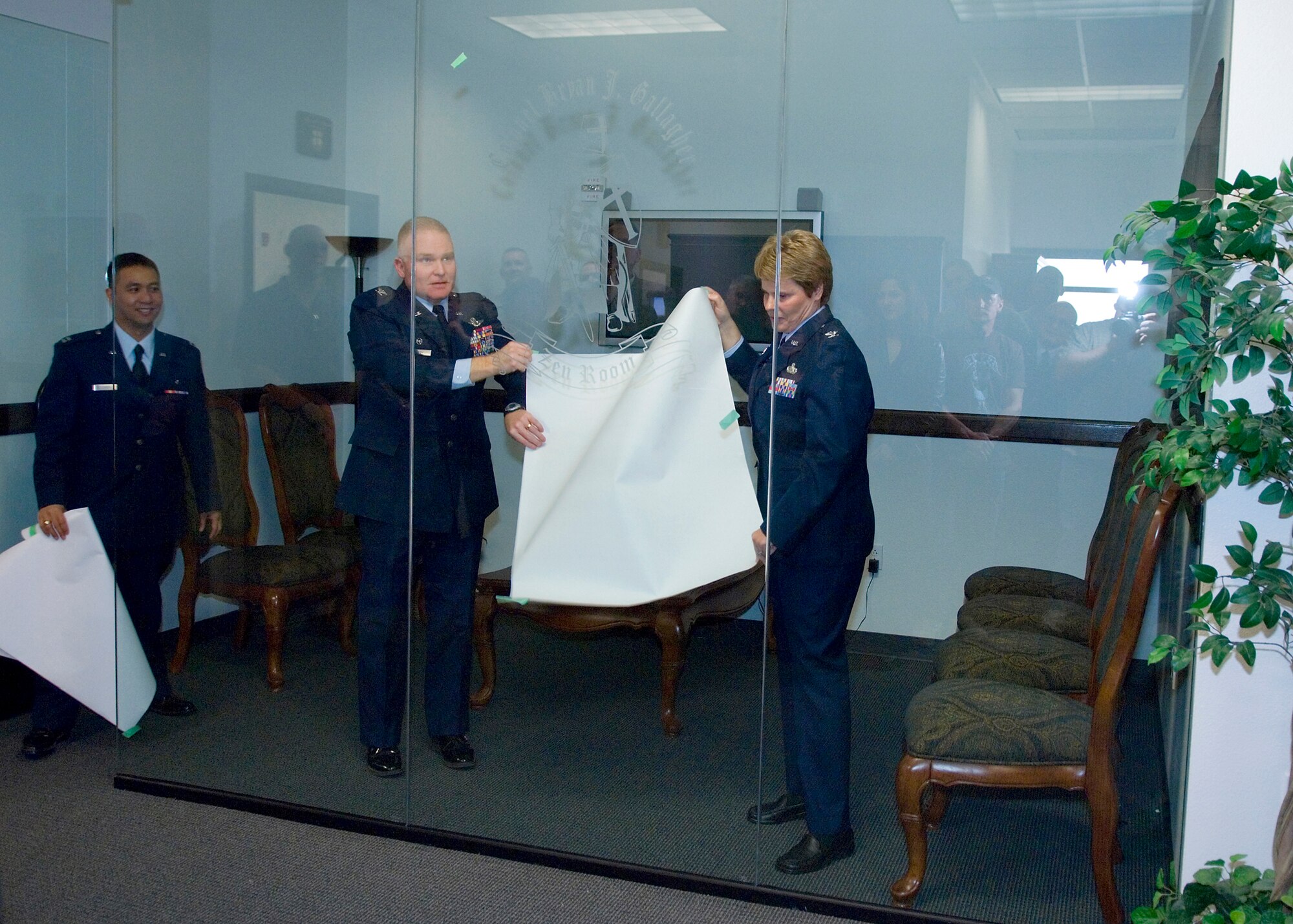 As part of a memorial ceremony, Col. Jerry Gandy (middle), 95th Air Base Wing commander, and Col. Nancy Reeves-Flores (right), 95th ABW vice commander, unveil the Colonel Bryan Gallagher Zen Room at the 95th ABW Command Section Feb. 5 as Capt. Leonardo Somera III, 95th ABW executive officer, looks on. (Air Force photo by Mike Cassidy)