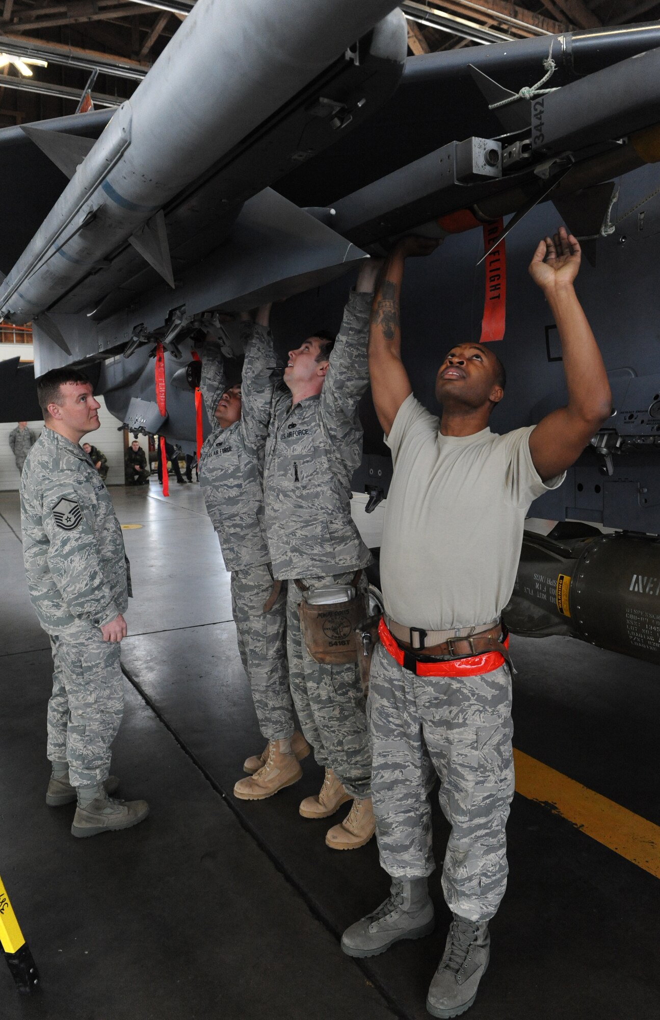 MOUNTAIN HOME AIR FORCE BASE, Idaho -- Senior Airman Brandon Armstrong,(right), Staff Sgt. Robert Bruner, (middle) and Airman 1st Class Emad Hamedeyyeh (left), all 391st Aircraft Maintenance Unit weapons load technicians, load an Aim-9 as Master Sgt. Summers, 366th Maintenance Group, judges during the base's weapons load crew of the year competition Feb. 5. The 391st AMU finished with a time of 50:17 and the 390th AMU crew finished with a time of 34:38. The winners will be announced during the 366th Operations Group banquet in April. (U.S. Air Force photo/ Airman 1st Class Debbie Lockhart)
