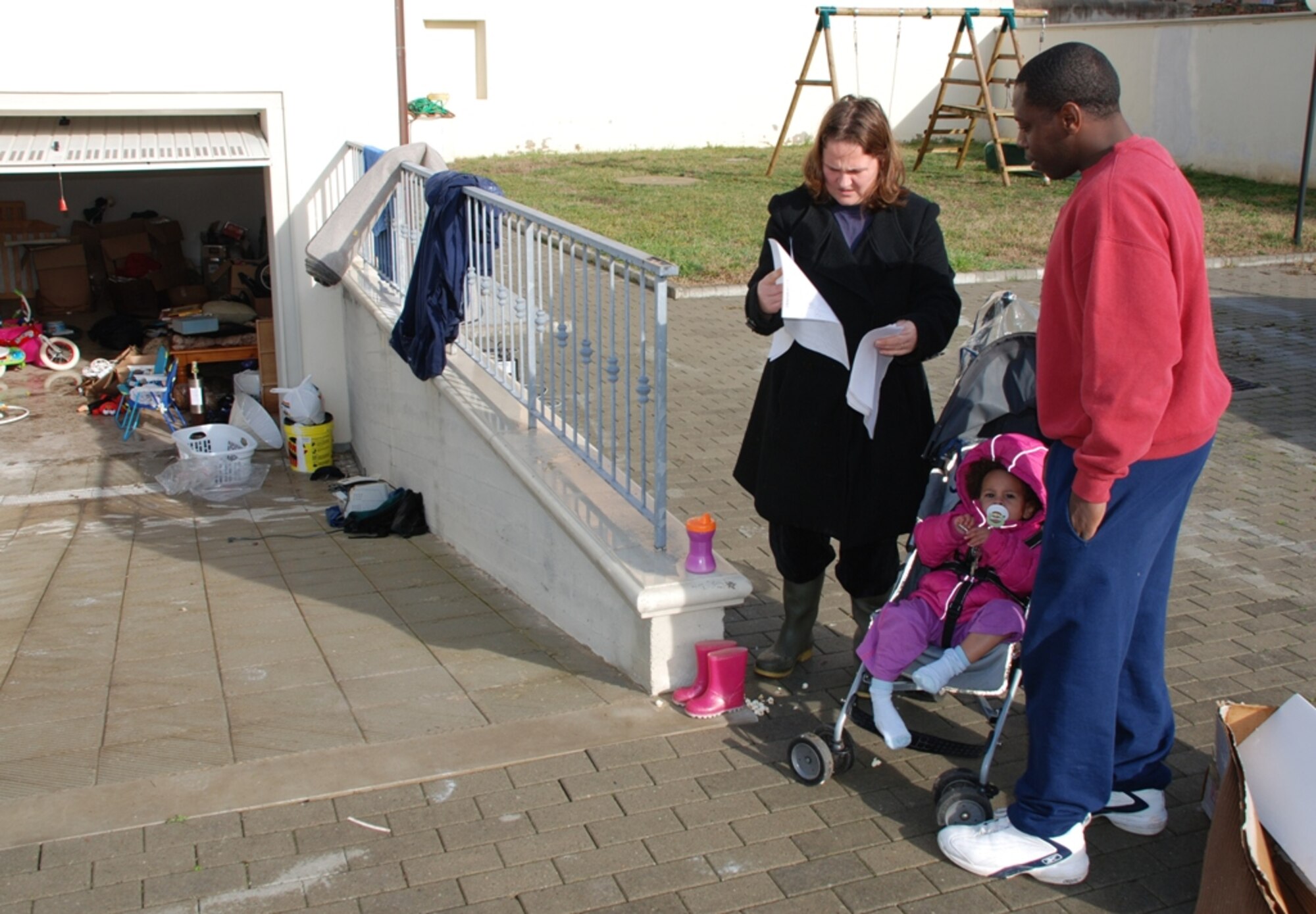 Master Sgt. Levern and Michelle Hughes, 31st Munitions Squadron, look over claims forms Feb. 9 as their daughter Amelia waits patiently for them to finish.  The Hughes' as did other families, ensured all items destroyed by the Feb. 6 flood which hit Pisa, Livorno and Camp Darby, Italy, areas, were properly annotated on the claims paperwork.  (U.S. Army photo by Joyce Costello.)