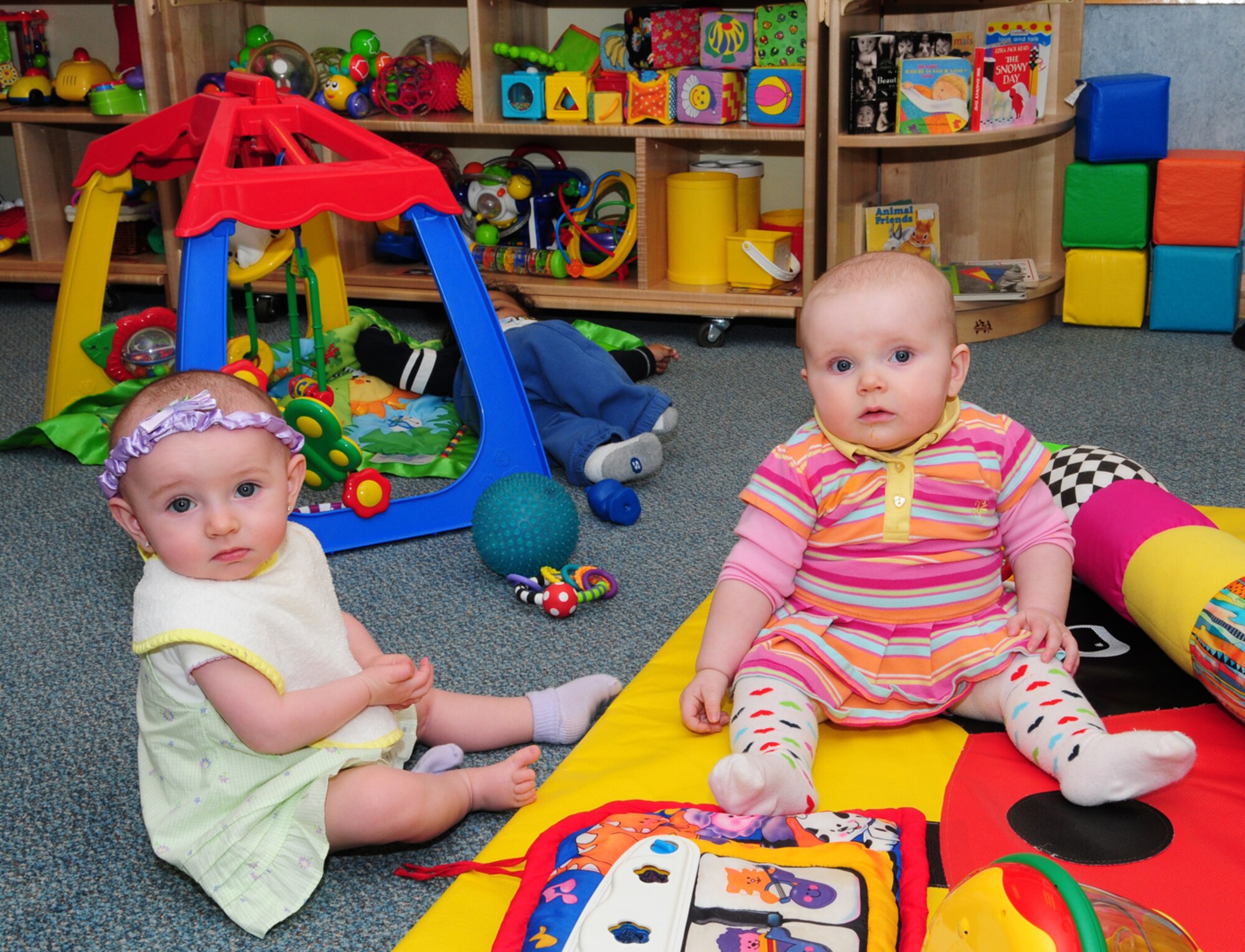 Kylie Bussard, left, 7 months, and Parker Jackson, right, 6 months, wait patiently for lunchtime, as Jamari Middelton, 6 months, also takes it easy in one of the two infant rooms at the CDC. Two new infant rooms are now available -- one for children  6 weeks to 6 months old, and another for children aged 6 to 12 months. By doing this, the CDC has doubled its capacity for those age groups. (U.S. Air Force photo by Karen Abeyasekere)