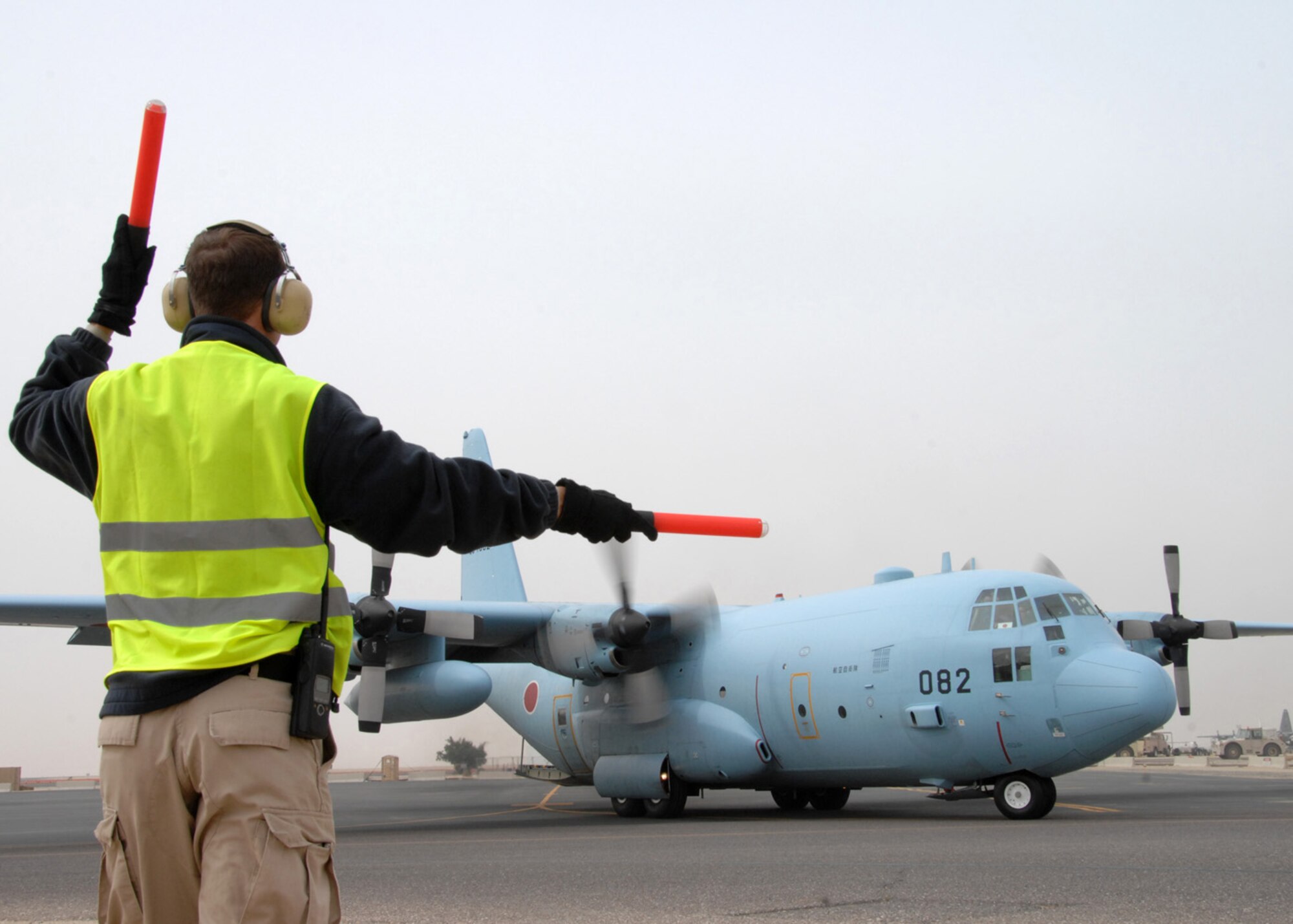 SOUTHWEST ASIA -- Jeff Schiebout, 386 Expeditionary Maintenance Squadron Transient Alert, guides a Japanese Air Self Defense Force C-130 as they taxi to the runway for their flight home at an air base in Southwest Asia, Feb. 10. Since 2004 the JASDF have been providing airlift for the Coalition forces and United Nations in support of Iraqi reconstruction efforts. (U.S. Air Force photo/ Senior Airman Courtney Richardson)