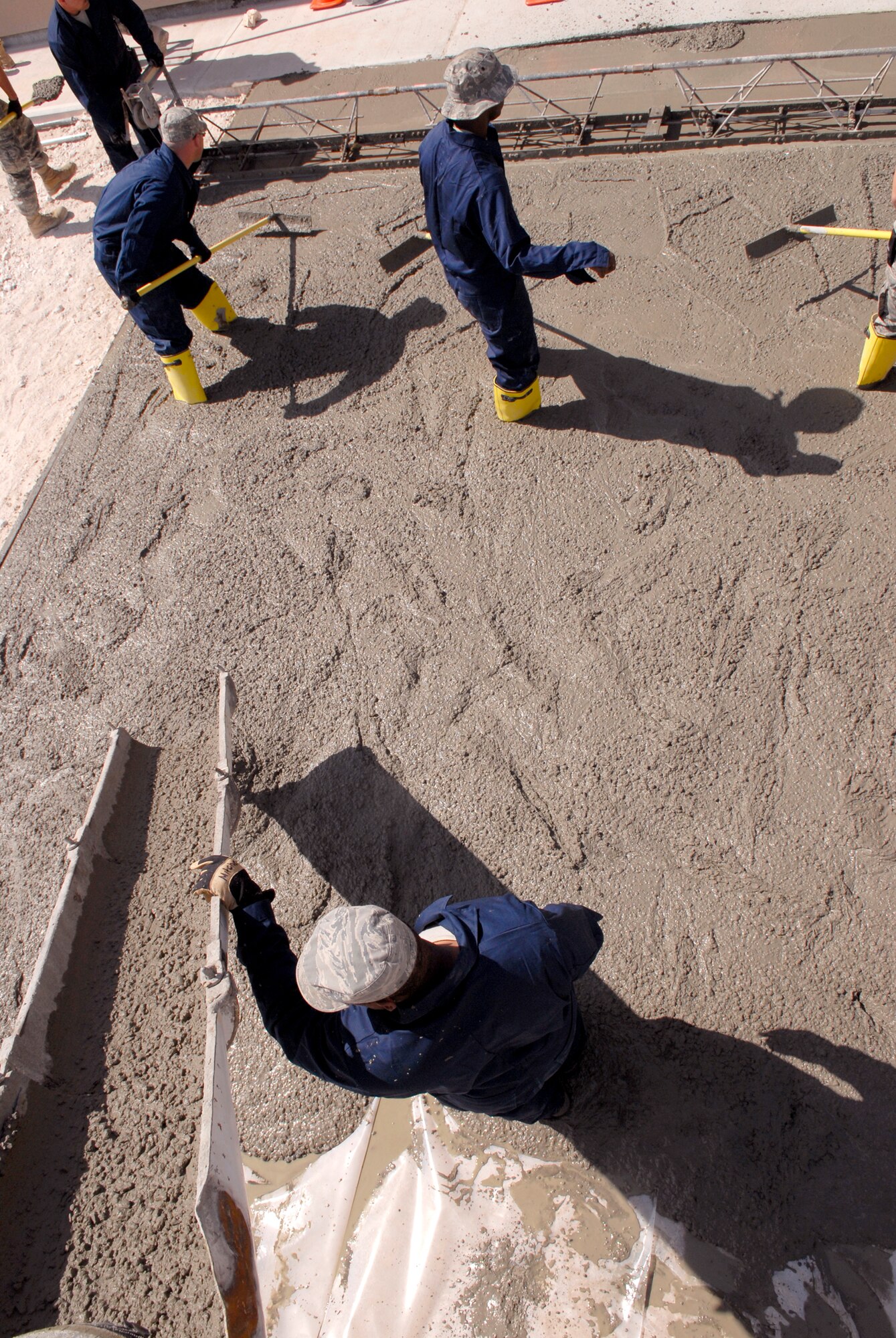 Airmen from the 379th Expeditionary Civil Engineer Squadron smooth and even out concrete for a new loading dock at the base Individual Equipment and Supply store,  Feb. 9, 2009 in an undisclosed location in Southwest Asia in support of Operation Iraqi and Enduring Freedom and Combined Joint Task Force- Horn of Africa.  (U.S. Air Force Photo by Airman 1st Class Andrew Satran/Released)