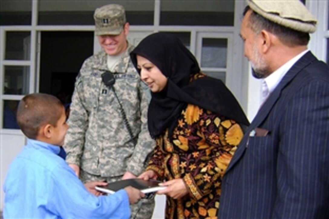 Mina Wali, Hope of Mother director, presents a notebook to a student for scoring the highest exam grade in his class, Feb. 4, 2009, while U.S. Air Force Capt. Dustin Hart, Nangarhar Provincial Reconstruction Team, and Surkh Rod sub-governor Said Ali Akbar, look on. The Hope of Mother School educates more than 400 students in the rural Sham Shapur village in Surkh Rod District, Afghanistan.

