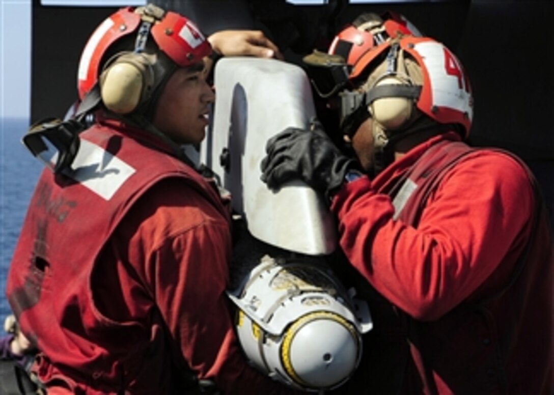U.S. Navy Petty Officer 3rd Class Derrick Cruz (left) and Airman Steven Brown of Strike Fighter Squadron 87 affix ordnance to the wing of an F/A-18A+ Hornet fighter aircraft aboard the aircraft carrier USS Theodore Roosevelt (CVN 71) underway in the Gulf of Oman on Feb. 4, 2009.  The ship and embarked Carrier Air Wing 8 are operating in the U.S. 5th Fleet area of responsibility.  
