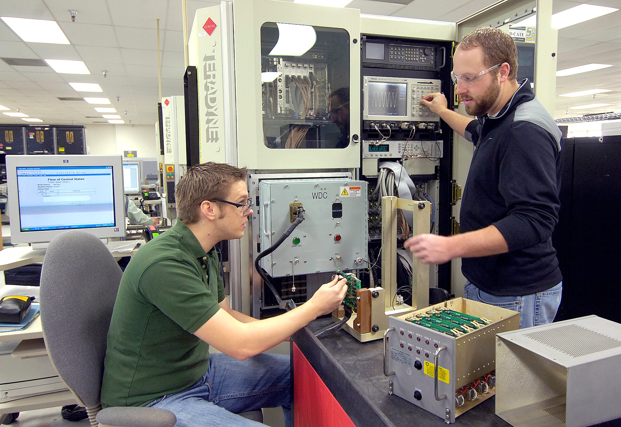 As Tinker electrical engineers with the 555th Software Maintenance Squadron, Geoffrey Dolinger, left, and Jeff Watson use sophisticated testers in Bldg. 3707 to ensure line replaceable units such as a C-17 window defogger operate perfectly. The squadron designs software and hardware using the newest technologies available in an ongoing effort to keep the warfighter in the air. (Air Force photo/Margo Wright)