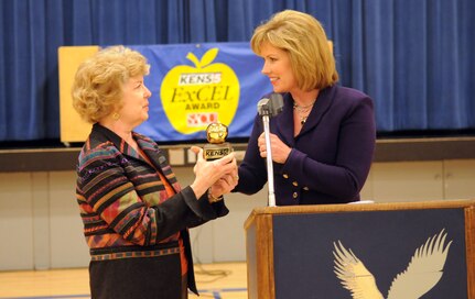 Debra Knapp, KENS 5 news anchor, presents the KENS 5/San Antonio Credit Union "Golden Apple ExCel Award" for teaching excellence to Donna Colglazier, an English teacher at Randolph High School on Feb. 10. (U.S. Air Force photo by Rich McFadden)