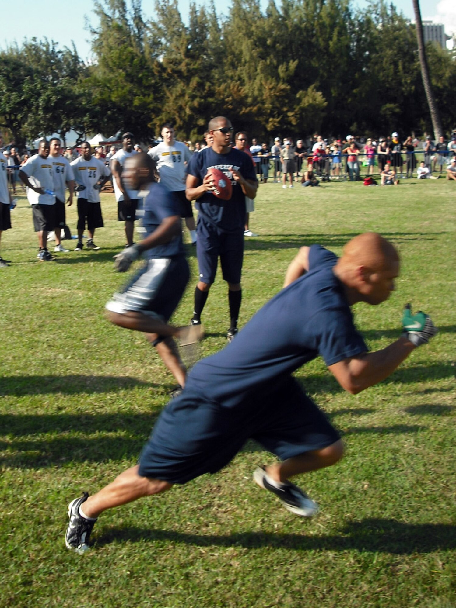1st Lt. Nate Allen (front) takes off for the final pass of the quarterback challenge as Capt. Marcus Fox crosses the line Feb. 7 during the NFL Military Challenge in Oahu's Kapiolani Park.  Capt. Dwayne Clark completed all eight of his pass attempts, most notably the record-setting 43 yard toss to Lieutenant Allen on the competition's final play. (U.S. Air Force photo/Mark Munsey)