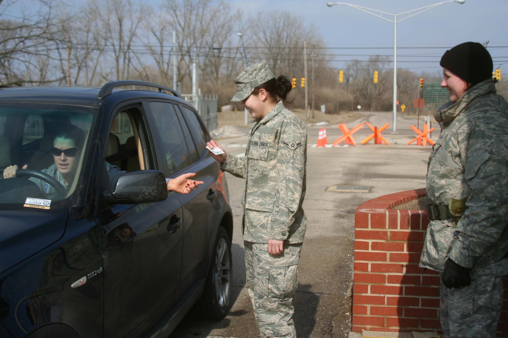 WRIGHT-PATTERSON AFB, Ohio - Senior Airman Theresa Grof, 445th Logistics Readiness Squadron, watches as Airman Esperanza Provencio, 88th Surgical Operations Squadron, checks the ID of a driver entering the base near the 445th AIrlift Wing.  Both airmen volunteered to help man the gate for the day. (Air Force photo/Staff Sgt. Amanda Duncan)