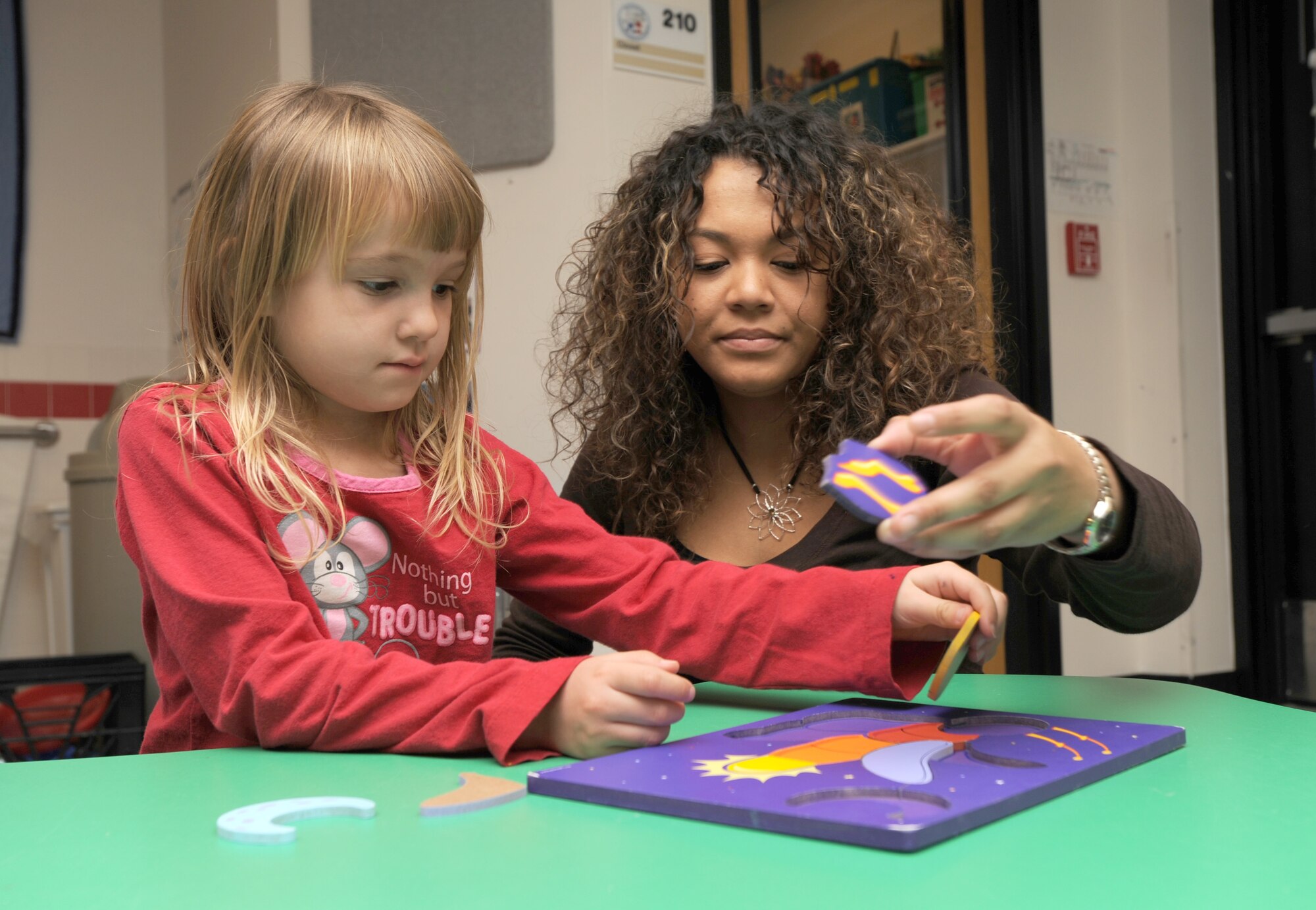 MCCONNELL AIR FORCE BASE, Kan. -- Jessica Rogers assists Chloe Miller, 5, daughter of Staff Sgt. Leslie Miller, 22nd Medical Group, on a children’s puzzle during the Give Parents a Break at the Child Development Center, Feb. 6. Give Parents a Break is an Air Force Aid Society funded Airman and Family Services Flight run program. It allows military parents an opportunity to enjoy time to themselves from their children.  (Photo by Senior Airman Roy Lynch) 