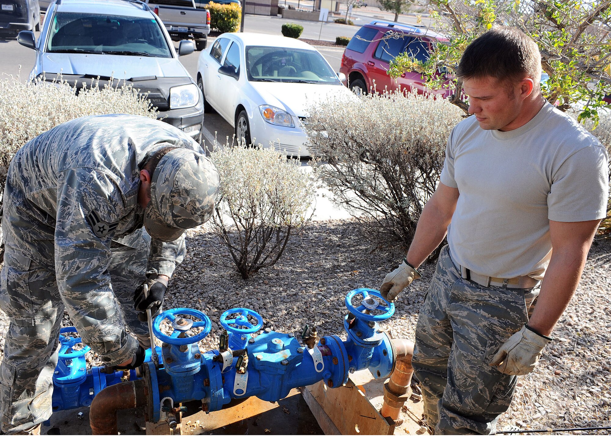 Staff Sgt. Destrey Robbins, 49th Civil Engineer Squadron, watches Airman First Class Jake Kinslow as he repairs a water main outside of Building 224 at Holloman Air Force Base, N.M., Feb. 6. Airman Kinslow and Sergeant Robbins worked together to fix the problem. (U.S Air Force photo/ Airman 1st Class DeAndre Curtiss)