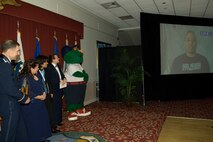 HANSCOM AIR FORCE BASE, Mass. – Senior Master Sergeant Raul Ruiz, 66th Mission Support Squadron first sergeant, speaks by video to the crowd gathered for the 66th Air Base Wing Annual Awards banquet Feb. 6, looking on are from left to right, Colonel Orr, 66th Air Base Wing commander, Sergeant Ruiz’s wife Brandi and son Ryan, Chief Master Sgt. Karen McCoy, ESC Command Chief and Boston Red Sox mascot Wally the Green Monster. Sergeant Ruiz was enroute to his deployed location during the banquet, he was named the 66th Air Base Wing First Shirt of the year, his wife and son accepted the award on his behalf. (U.S. Air Force photo by Rick Berry) 