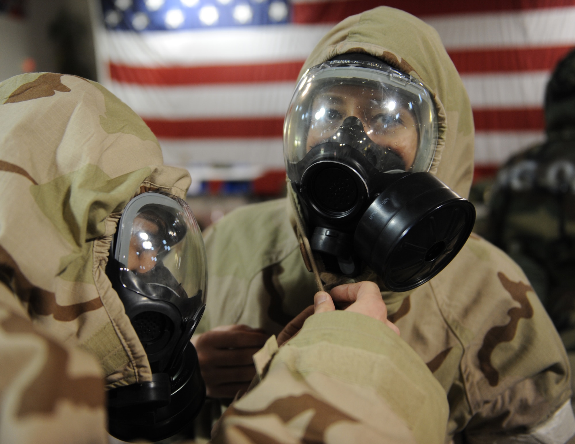 WHITEMAN AIR FORCE BASE, Mo. – Capt. Saleem Razvi, 509th Bomb Wing Legal Office, tightens the draw strings on 1st Lt. Amy Blanco’s, 509th Communications Squadron, Mission Oriented Protective Posture suit during Ability To Survive and Operate training Feb. 11. The training provided and evaluated how well personnel use their chemical protection ensemble, how to recognize unexploded munitions and cordon off the areas to prevent other personnel from detonating the devices. (U.S. Air Force photo/Senior Airman Stephen Linch)