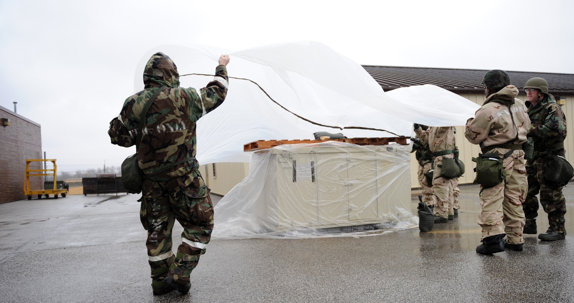 WHITEMAN AIR FORCE BASE, Mo. – Team Whiteman members cover an asset to protect it from potential chemical contamination during Ability To Survive and Operate training Feb. 11. The training provided and evaluated how well personnel use their chemical protection ensemble, how to recognize unexploded munitions and cordon off the areas to prevent other personnel from detonating the devices. (U.S. Air Force photo/Senior Airman Stephen Linch)