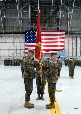Marine Lt. Col. Marcus Malais (left) receives the Medium Helicopter Squadron 764 colors from Lt. Col. David Cleary (right) during the HMM 764 change of command ceremony at hangar 1210 here Feb. 7. The HMM 764 is responsible for managing CH-46E Sea Knight transport helicopters. (Air Force photo by Jet Fabara)