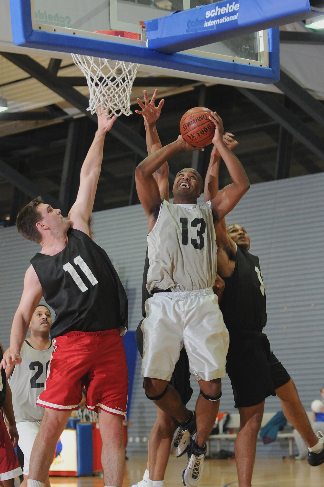 Staff Sgt. Kevin Patterson, No. 13 for the services team, goes up through three defenders and is fouled during the 30-and-over championship game against the medical group team Jan. 5, 2009, Ramstein Air Base. Services won with a score of 42-33. (U.S. Air Force photo by Senior Airman Nathan Lipscomb)