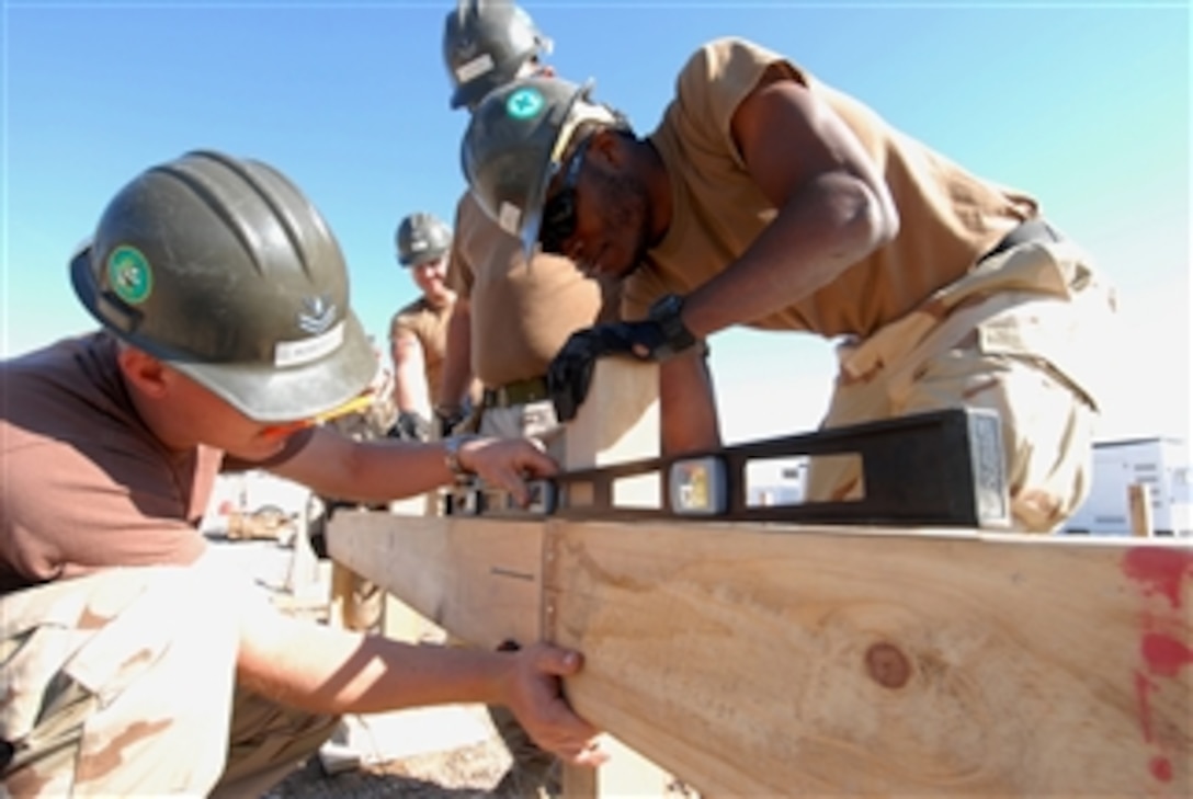 U.S. Navy Petty Officer 2nd Class Jeffrey Roberts uses a level to ensure a frame board is aligned properly as Seaman Michael Joseph holds it in place while making improvements to a patrol base in Mahawil, Iraq, on Feb. 4, 2009.  The Navy Seabees are from Amphibious Construction Battalion 2.  