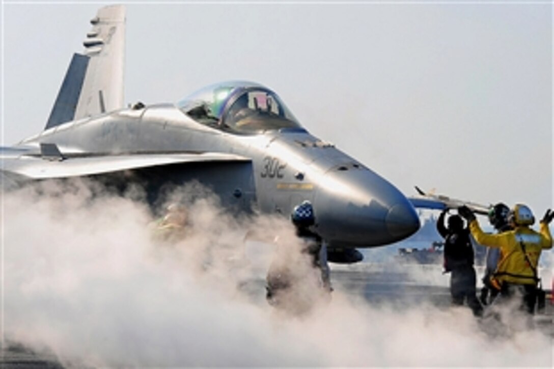 U.S. Navy crew members direct an F/A-18C Hornet toward a catapult during first event of flight operations aboard the aircraft carrier USS Theodore Roosevelt in the Gulf of Oman, Feb. 10, 2009.