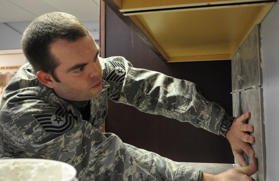 Tech. Sgt. Chad Dye, 33rd Fighter Wing facility improvement team volunteer, lays tile for a cabinet backsplash in the new Protocol Center at the wing's headquarters building Feb. 5. He gives his free time to help the team when he's not on the flight line maintaining avionics equipment on F-15 aircraft for the 33rd Maintenance Operations Squadron.  (U.S. Air Force Photo/Chrissy Cuttita)