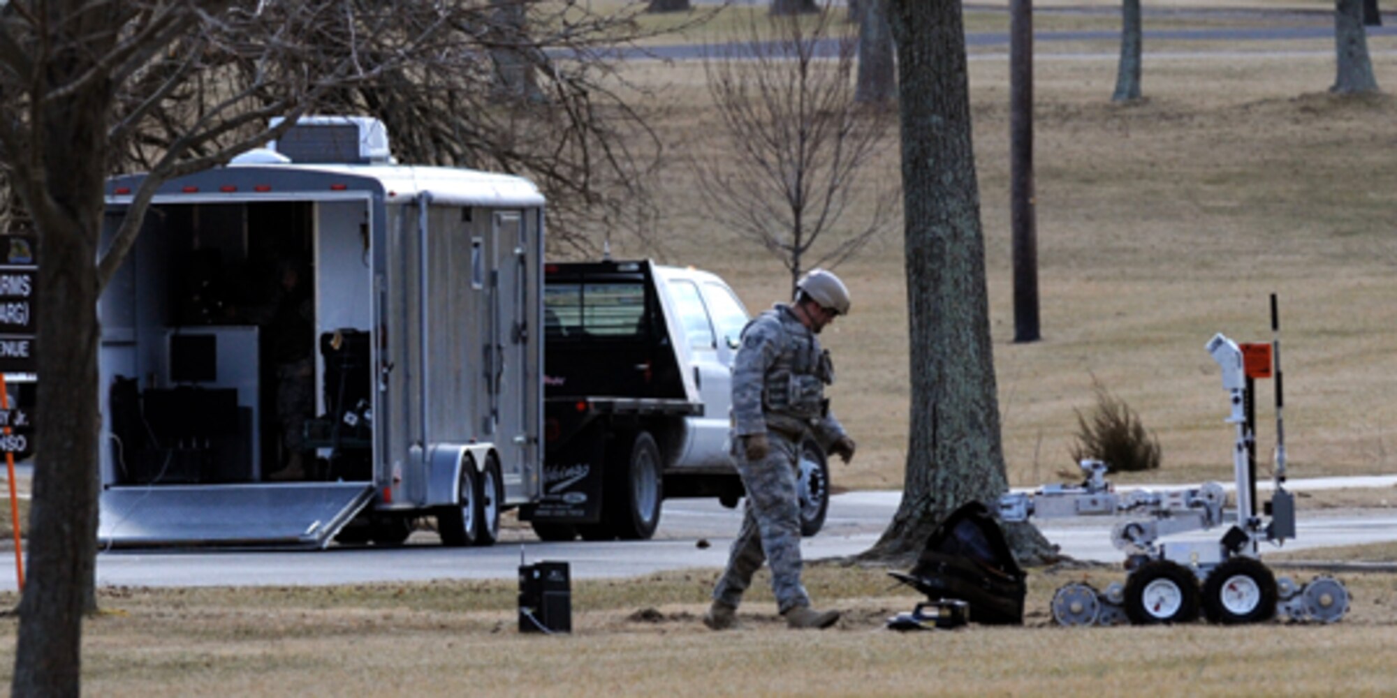 Staff Sgt. Joshua Mills, 305th Civil Engineer Squadron Explosive Ordnance team leader, visually inspects a suspicious package at Fort Dix Feb. 12. The team leaders’ inspection only comes after the EOD Robot F6A, known as the down range eyes and ears of EOD, does the first inspection remotely. The EOD team usually consists of three members; this team included Sergeant Mills, Senior Airman John Matthews, and Airman 1st Class Kala Jenkins, with the latter two working the F6A from inside the trailer. Fortunately, the suspicious package turned out to be a false alarm, but every threat is treated as the real thing. The McGuire EOD Flight responds to reports at McGuire, Fort Dix, Lakehurst and Fort Monmouth and provides support to surrounding law enforcement. (U.S. Air Force Photo/Wayne Russell)