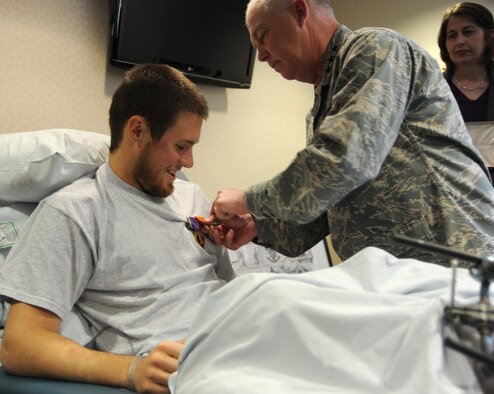 EGLIN AIR FORCE BASE, FL -- Commander of Air Force Special Operations Command, Lt. Gen. Donny Wurster, pins the Air Force Combat Action Medal to Senior Airman Alex Eudy's shirt during an informal ceremony at the hospital here Feb. 3.  Airman Eudy also received The Purple Heart for injuries he received during his deployment in Afghanistan. An improvised explosive device destroyed the vehicle he and five other U.S. military members were traveling in Jan. 23. All six survived the attack. Airman Eudy, a special operations weatherman in the 10th Combat Weather Squadron at Hurlburt Field, FL, is on the mend and in good spirits after extensive surgery to his lower legs. (U.S. Air Force photo by Chief Master Sgt. Ty Foster) 
