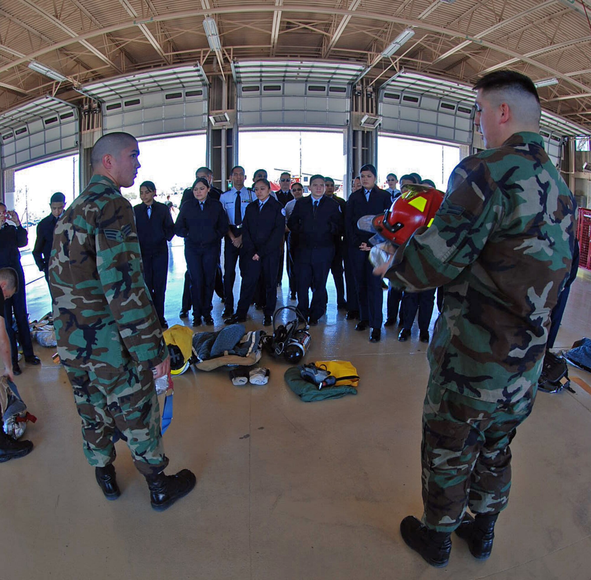 LAUGHLIN AIR FORCE BASE, Texas –Senior Airman Andrew Lira and Airman 1st Class Andrew Sanchez, Laughlin fire department, explain and demonstrate how they use their equipment when fighting fires to a group of Del Rio High School Junior Reserve Officer Corps students during their day-long tour of Laughlin Feb. 11. The Fire fighters also allowed the students try on their gear and equipment and explore their heavy duty trucks. (U.S. Air Force photo by Airman 1st Class Sara Csurilla)