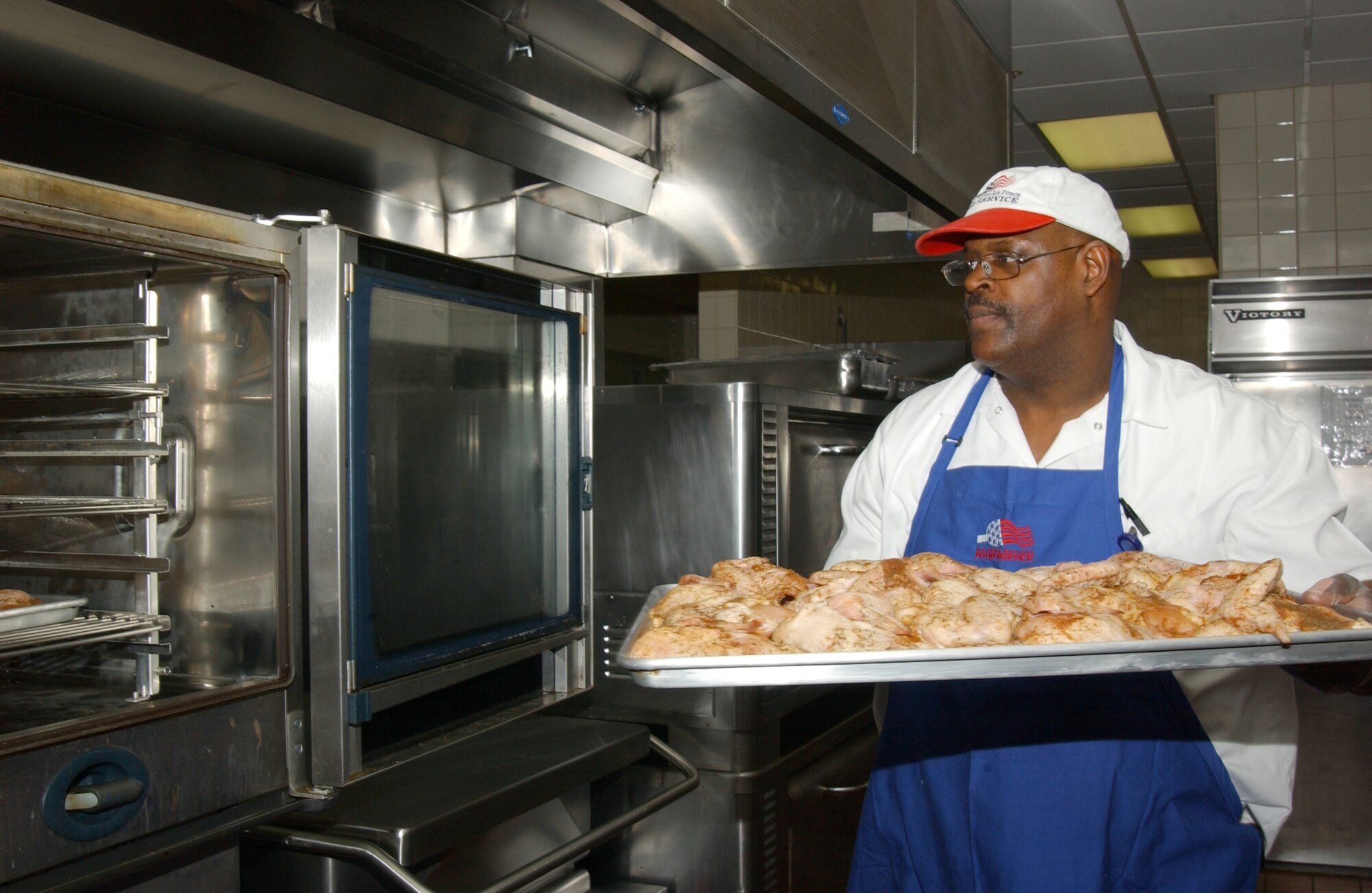 SCOTT AIR FORCE BASE, Ill. -- Challenge Unlimited food service worker, Edward Jenkins, places chicken legs in an oven making them hot and fresh for hungry Airmen coming through the Dining Facility for lunch. (U.S. Air Force photo/Airman 1st Class Amber Kelly-Woodward)