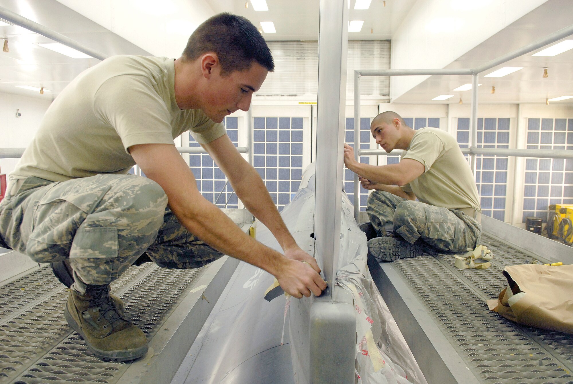 Senior Airman Troy Anderson and Airman 1st Class Jacob Hefly, 56th Equipment Maintenance Squadron aircraft structural maintenance technicians, remove tape and plastic from aircraft 178 after painting on Jan. 29. Aircraft 178, which has the most flying hours of all aircraft at Luke, had sections repainted before being transferred to the 162nd Fighter Wing in Tucson. (U.S. Air Force photo/Staff Sgt. Ian Dean)
