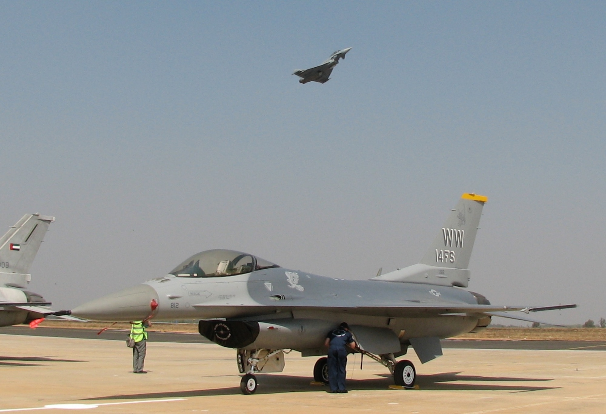 A Luftwaffe Eurofighter conducts aerobatic maneuvers  over an F-16 Fighting Falcon Feb. 9 during a demonstration at the Aero India 09 air show at Air Force Station Yelahanka, India. The F-16, along with a C-17 Globemaster III, C-130J Hercules, KC-135 Stratotanker, F/A-18 Hornet and an Eagle Vision ground satellite system, are on hand at the air show, demonstrating U.S. capabilities and commitment to the Pacific region. (U.S. Air Force photo/Maj. Sam Highley)