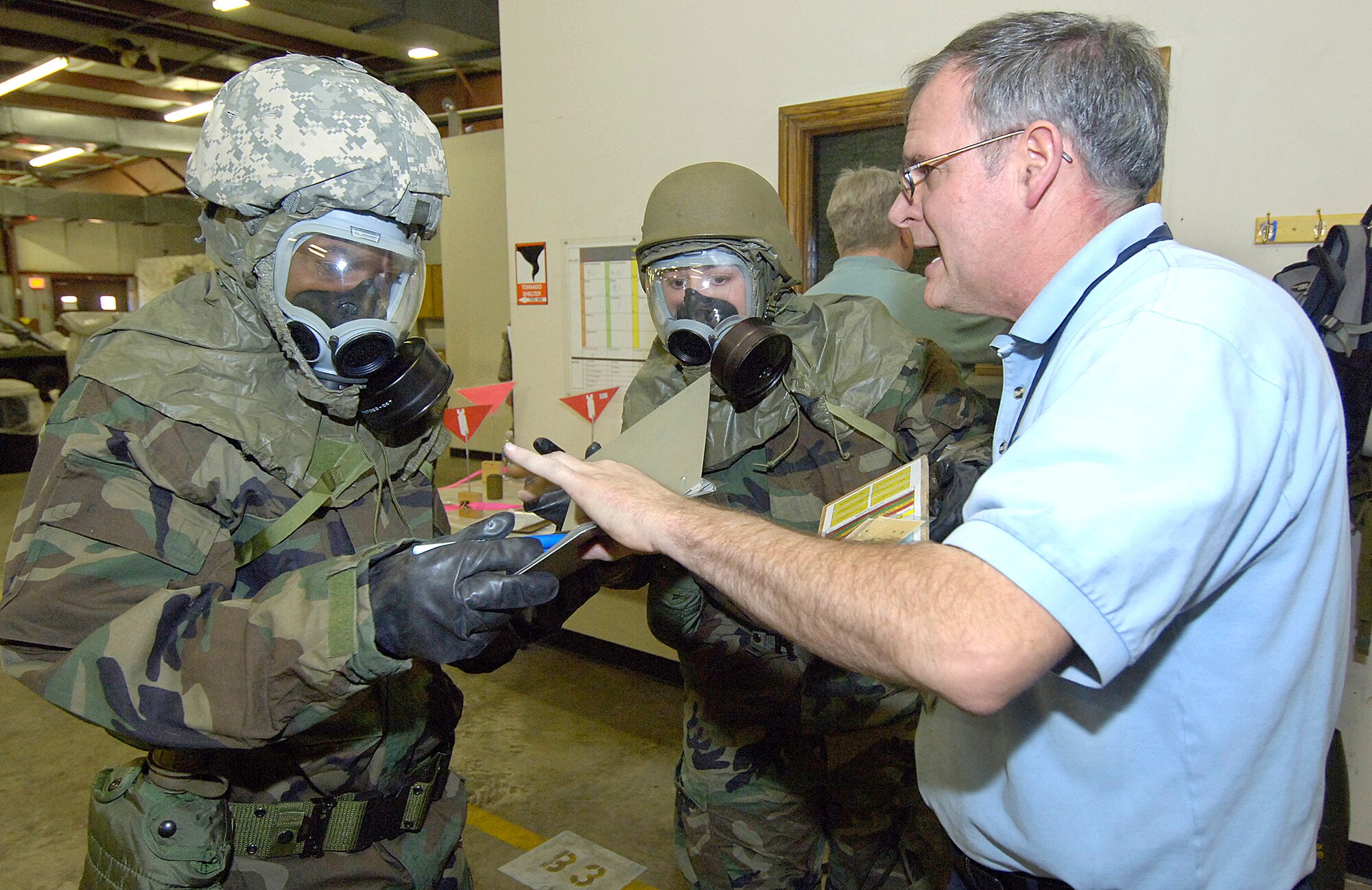 Instructor Ted Hunter explains post-attack reconnaissance procedures during recent Warrior Day training in Bldg. 1115.  One-hour classes in Self Aid/Buddy Care, weapons, and correct wearing of personal protective gear, help Airmen like 1st Lt. Tiji Allen, left, and Staff Sgt. Michelle Murphy, stay sharp on the basics. Lieutenant Allen and Sergeant Murphy are with the 72nd Force Support Squadron, Military Personnel Section. (Air Force photo/Margo Wright)