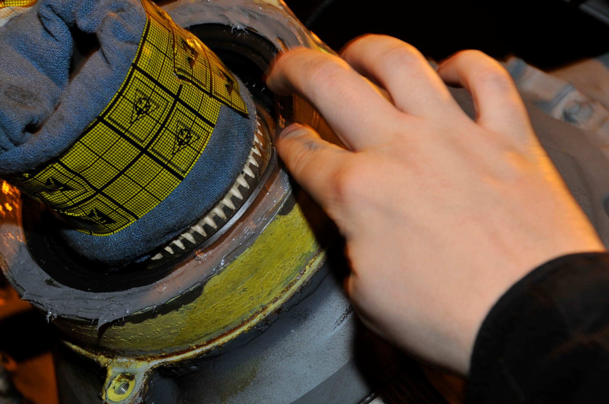 Staff Sgt. Seth Nehiley, 56 Aircraft Maintenance unit crew chief, uses his finger to wipe off excess sealant Jan. 27 at RAF Lakenheath, England. The sealant will help keep the fluid inside the gear box to prevent it from burning up when in flight. (U.S. Air Force photo by Airman 1st Class Perry Aston)