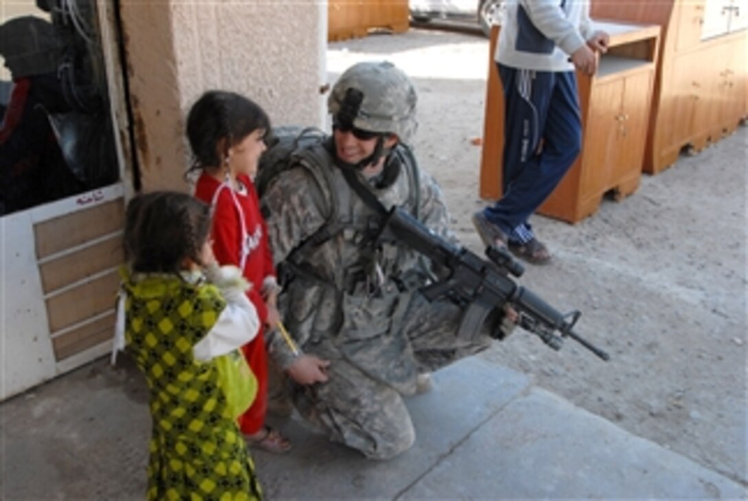 U.S. Army Pfc. Toby Barnes of 2nd Brigade Combat Team, 4th Infantry Division talks to two Iraqi girls during a joint patrol with Iraqi police to conduct post-election surveys in Iman, Iraq, on Feb. 3, 2009.  