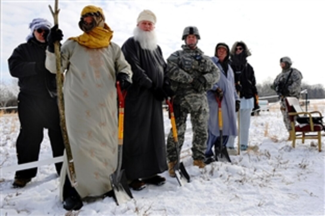 U.S. Army Col. Brian Copes, fourth from left, participates in a mock groundbreaking ceremony on a snowy day at the Muscatatuck Urban Training Center, a sub-installation of Camp Atterbury, Ind. The ceremony is part of the team's preparation to deploy to Khost province, Afghanistan, where they will participate in missions aimed at improving farming production. Copes, assigned to 1st Battalion, 19th Regiment, is Agribusiness Development Team commander.