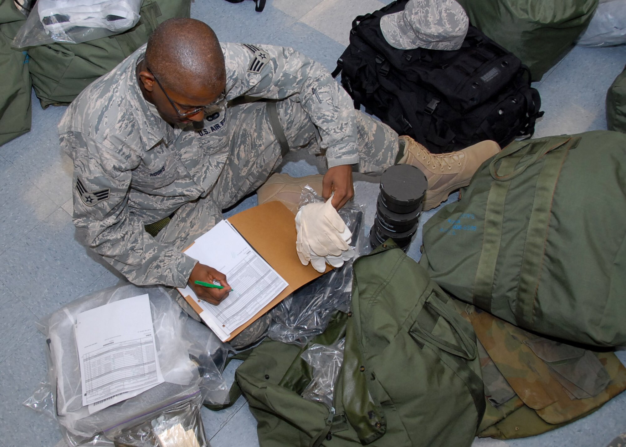 As part of the February base exercise, Senior Airman Larry Hooks of the Lemay Center checks the inventory of his “C” bag Wednesday. Each bag contains protective items in the event of a chemical attack. Airman Hooks was required to inspect his gear in a “deployment line” as the base exercised its mobility machine for actual deployments. (Air Force photo by Jamie Pitcher)