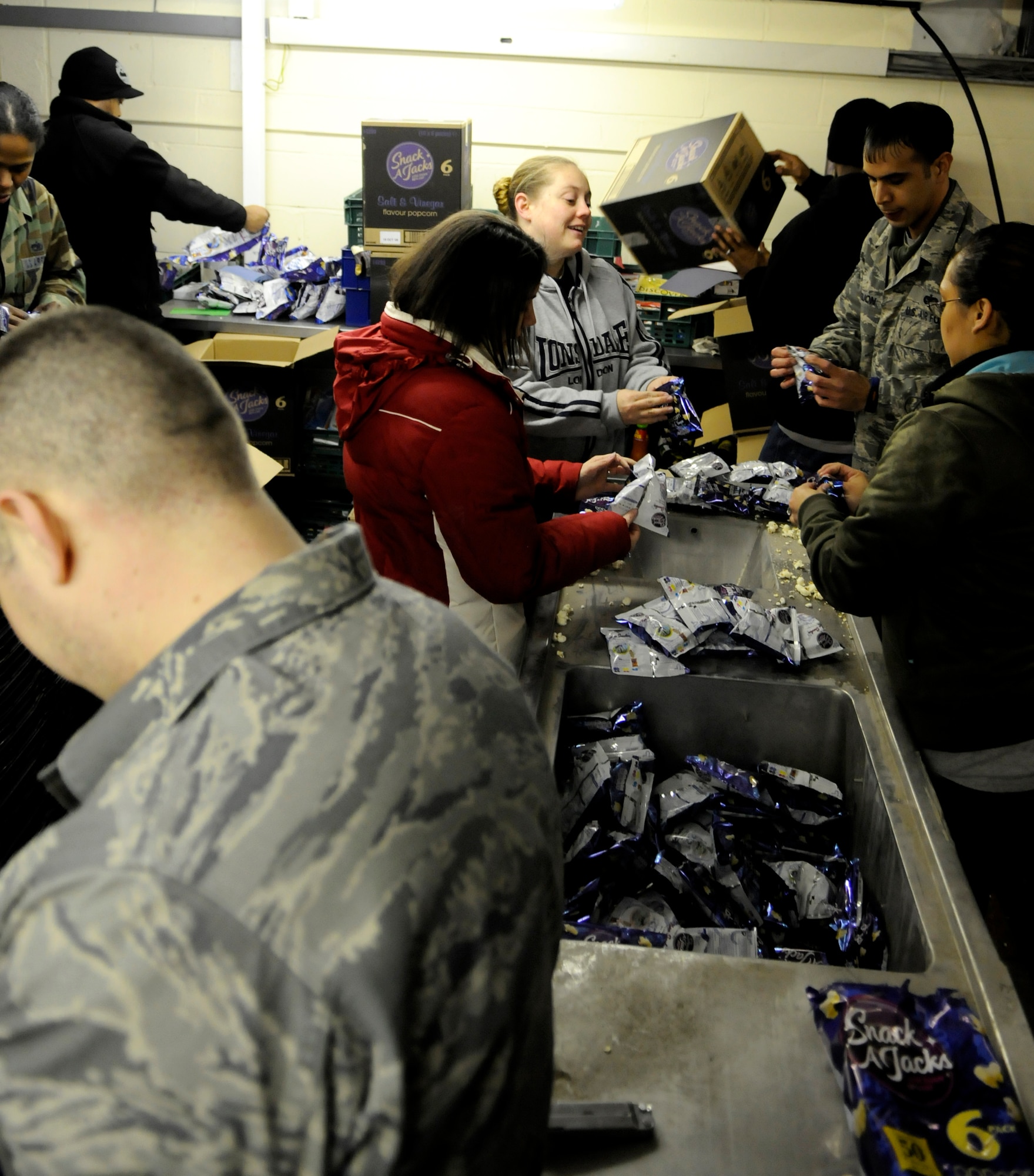 Staff Sgt. Sarah Stacy-Smith of the 352nd Operations Support Squadron (upper left), Staff Sgt. John Aguon of the Joint Special Operations Air Component Europe(upper right), Staff Sgt. Lisa Patsios (lower left) and Senior Airman Leticia Elias (lower right) both from the 488 Intelligence Squadron, empty out-of-date popcorn from snack bags so that is can be used as cattle feed instead of going into landfill at the Newmarket Open Door Feb 6, 2009. (U.S. Air Force photo by Senior Airman Christopher L. Ingersoll)