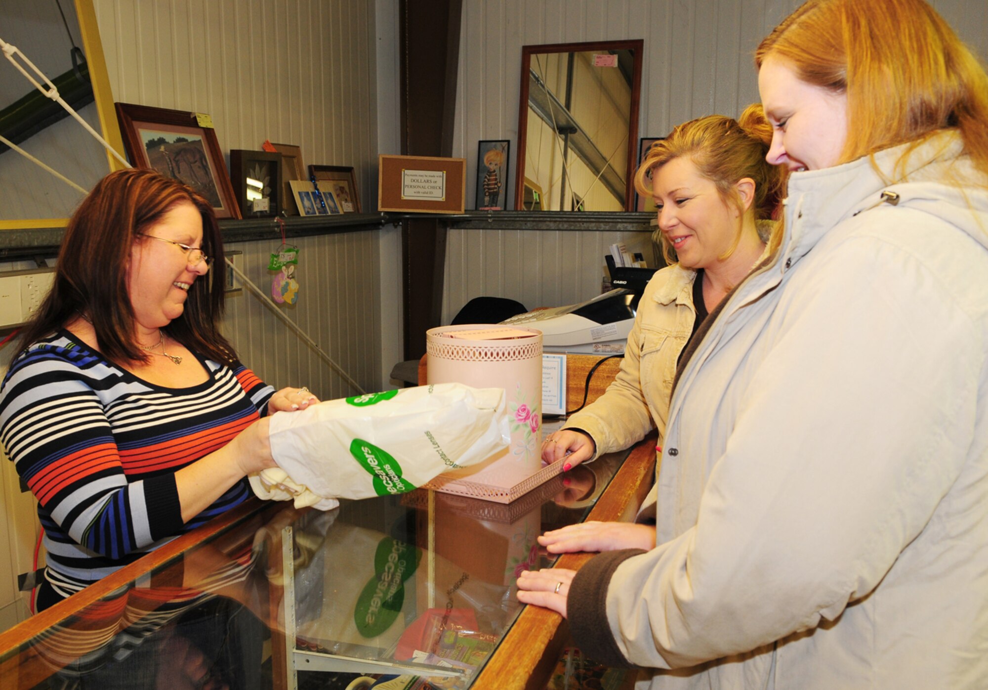 Kathy Hill, left, volunteer at RAF Mildenhall's thrift shop, helps customers Kelly Prior, right, and Tracy Worth Feb. 9. Both the thrift shop and community closet have moved; they are now located in Building 644 (formerly the arts and crafts facility, near the 100th Security Forces Squadron). (U.S. Air Force photo by Karen Abeyasekere)