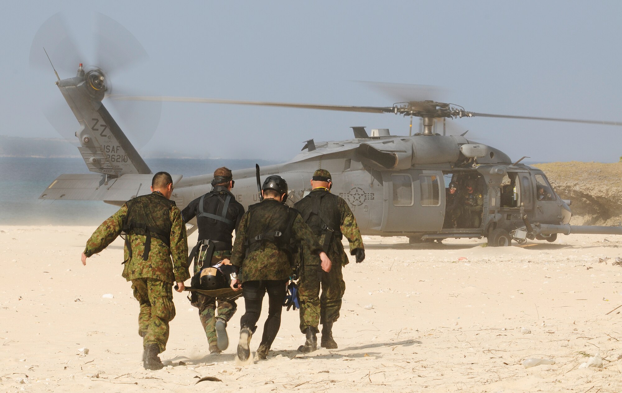 U.S. Air Force Pararescuemen and Japanese Air Self Defense Force (JASDF) Air Rescue personnel carry a simulated survivor to an HH-60 Pave Hawk helicopter on a beach off the coast of Okinawa, Japan during exercise Cope Angel 09-1, Feb. 12, 2009. Cope Angel is a joint rescue exercise between members of the U.S. Air Force and the JASDF. (U.S. Air Force photo/Airman 1st Class Chad Warren)
