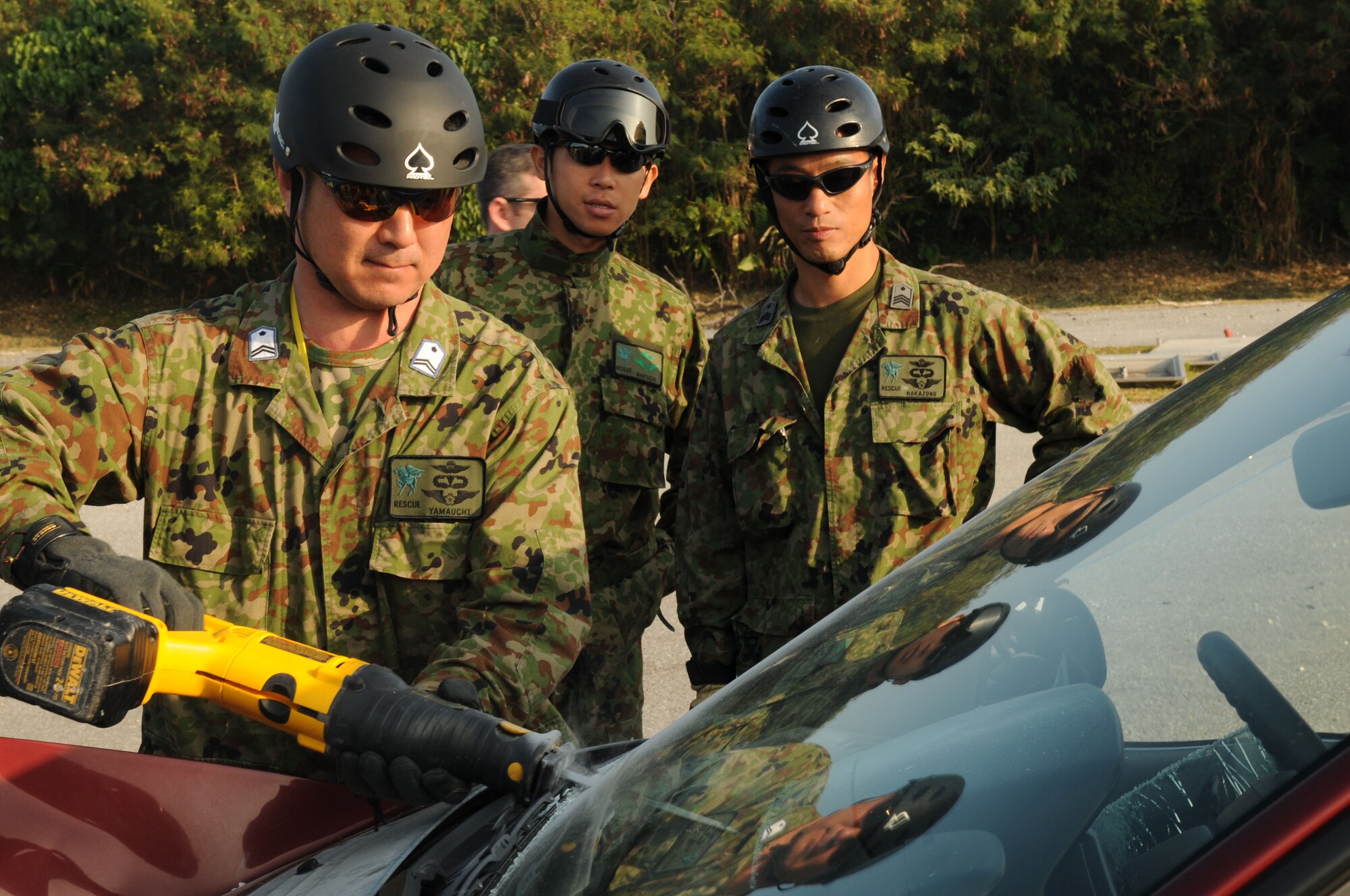 An Air Rescueman from the Japanese Air Self Defense Force (JASDF) uses a reciprocating saw to remove a car windshield as other members of the team watch over during exercise Cope Angel 09-1, Feb. 11, 2009. Cope Angel is a joint rescue exercise between members of the U.S. Air Force and the JASDF. (U.S. Air Force photo/Staff Sgt Chrissy Best)