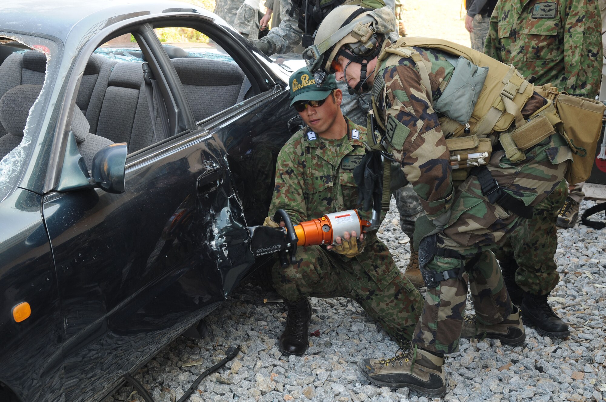Pararescuemen from the 31st Rescue Squadron at Kadena Air Base, Japan, and JASAF pararescuemen, use the jaws of life to force open a car door during exercise Cope Angel 09-1, Feb. 10, 2009. Cope Angel is a joint rescue exercise between members of the U.S. Air Force and the Japanese Air Self Defense Force. (U.S. Air Force photo/Staff Sgt Chrissy Best)