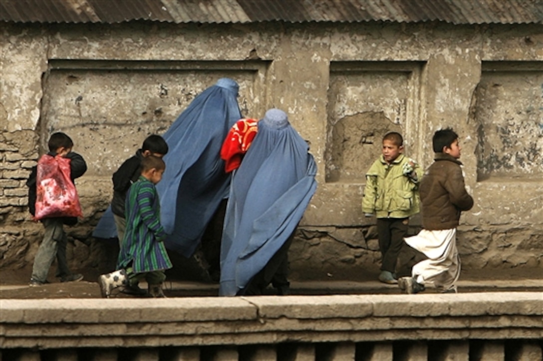 Two Afghan women clad in blue burkas and five children wearing a mix of Western and traditional clothing carry goods home from an Afghan market, Feb. 4, 2009. The photo was taken by U.S. Army National Guard Photographer Staff Sgt. Russell Lee Klika, who now serves with the 2nd Battalion, 19th Special Forces Group of the West Virginia Army National Guard. The unit recently deployed to conduct missions around the country in support of Operation Enduring Freedom XIII.